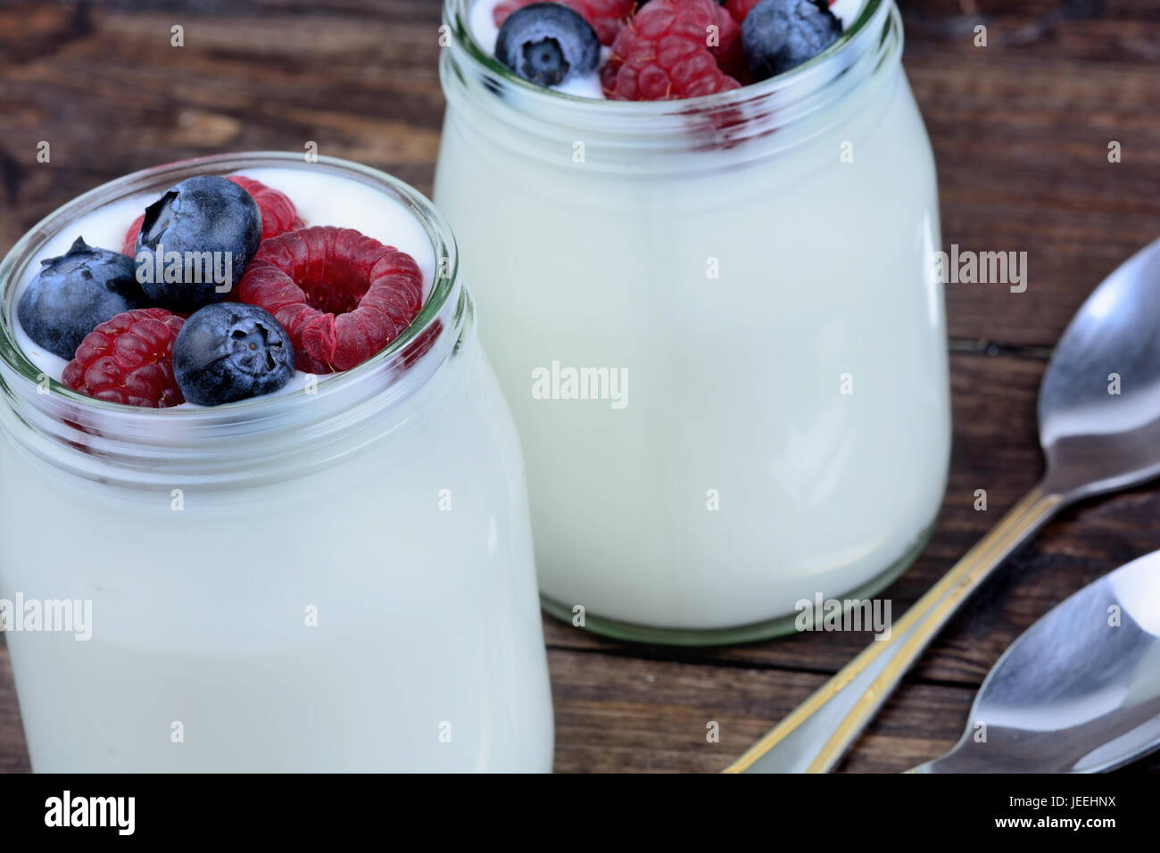 Yogurt with berries in a jars glass on table Stock Photo