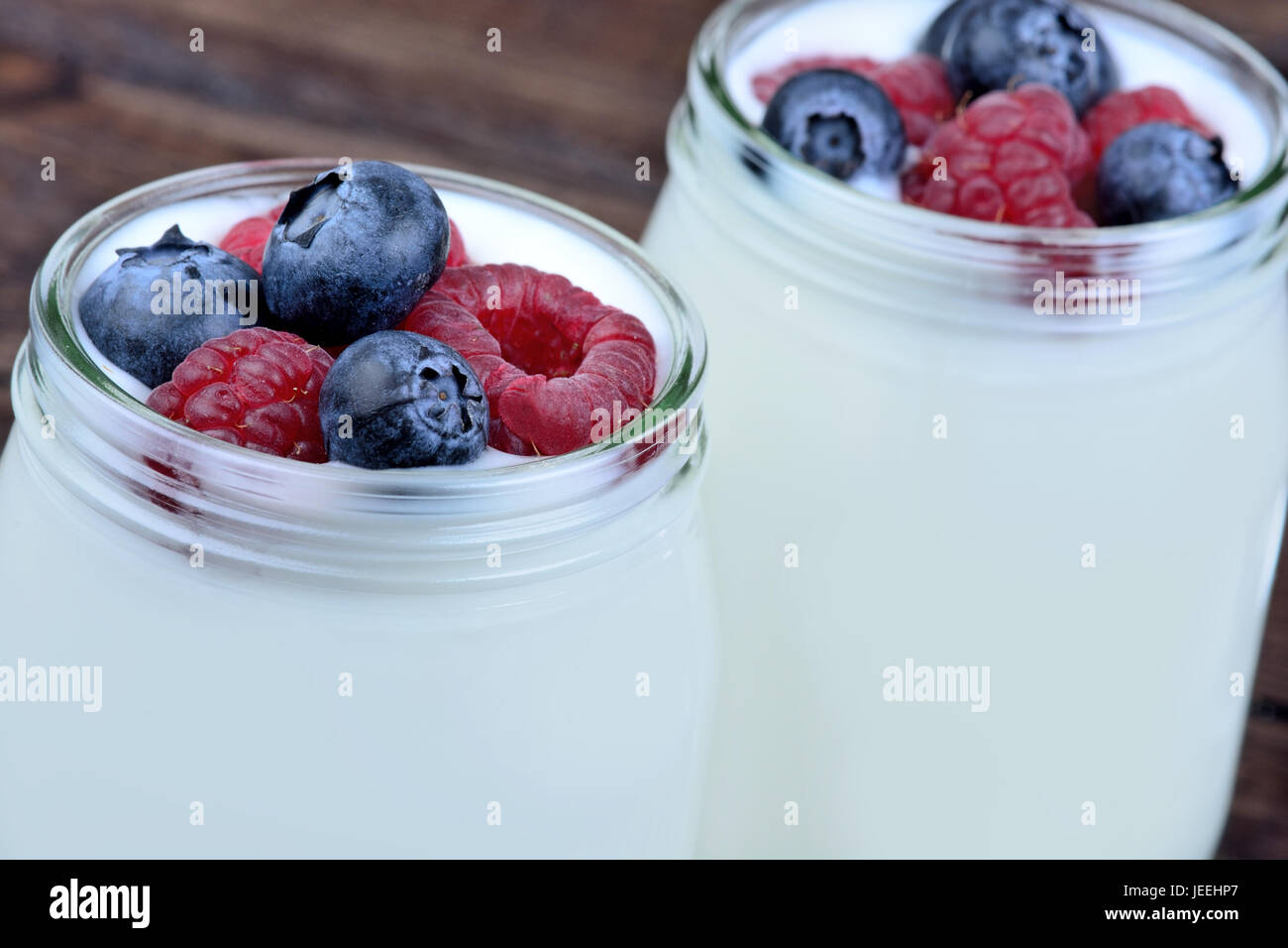Jars with yogurt ans assorted berries on wooden table Stock Photo