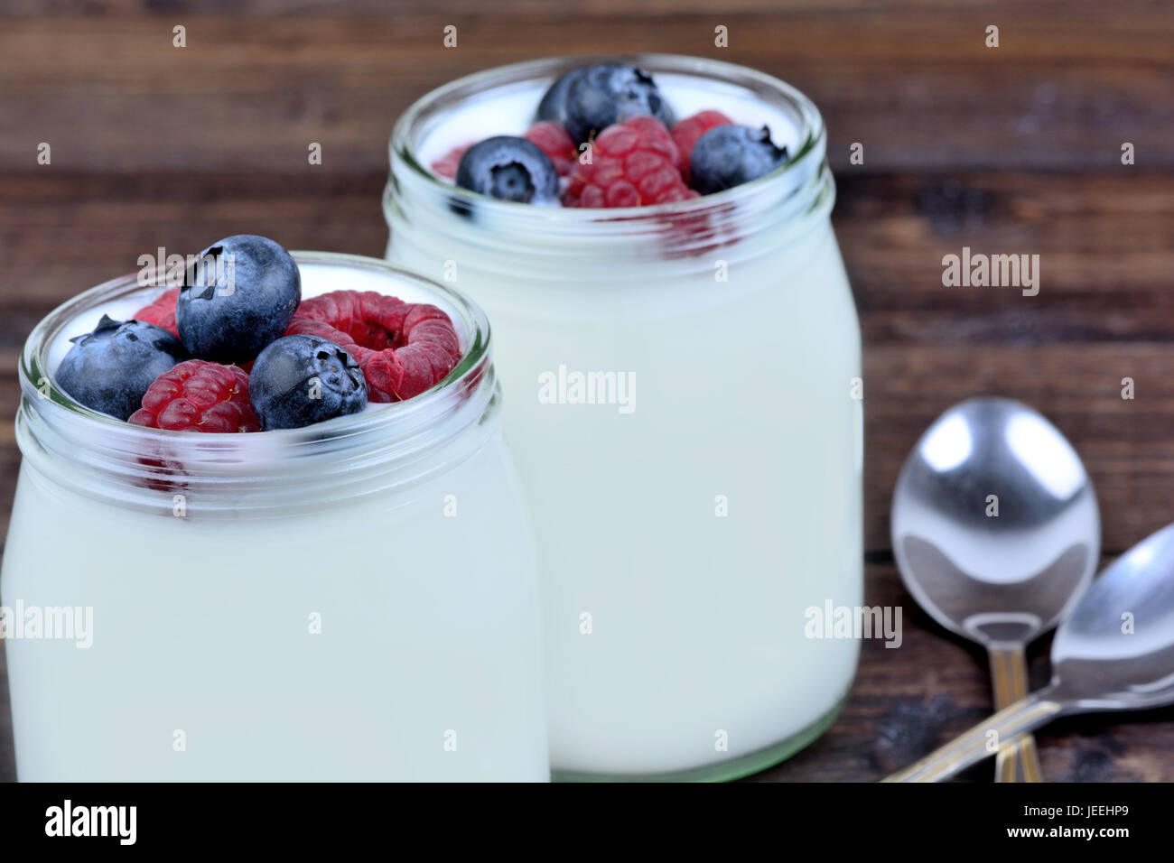 Jars with yogurt ans assorted berries on table close-up Stock Photo
