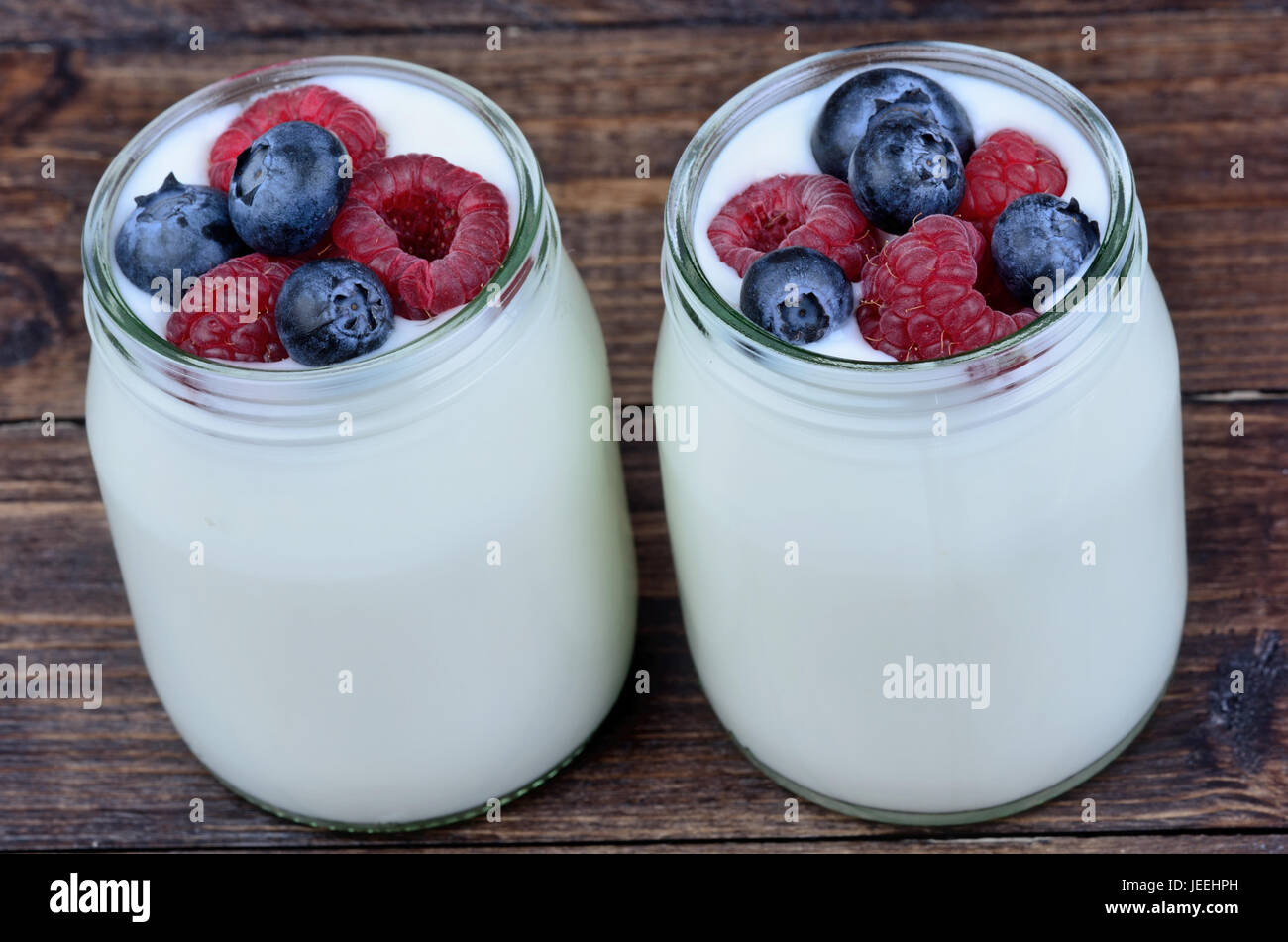 Assorted berries with yogurt in a jars glass on wooden table Stock Photo