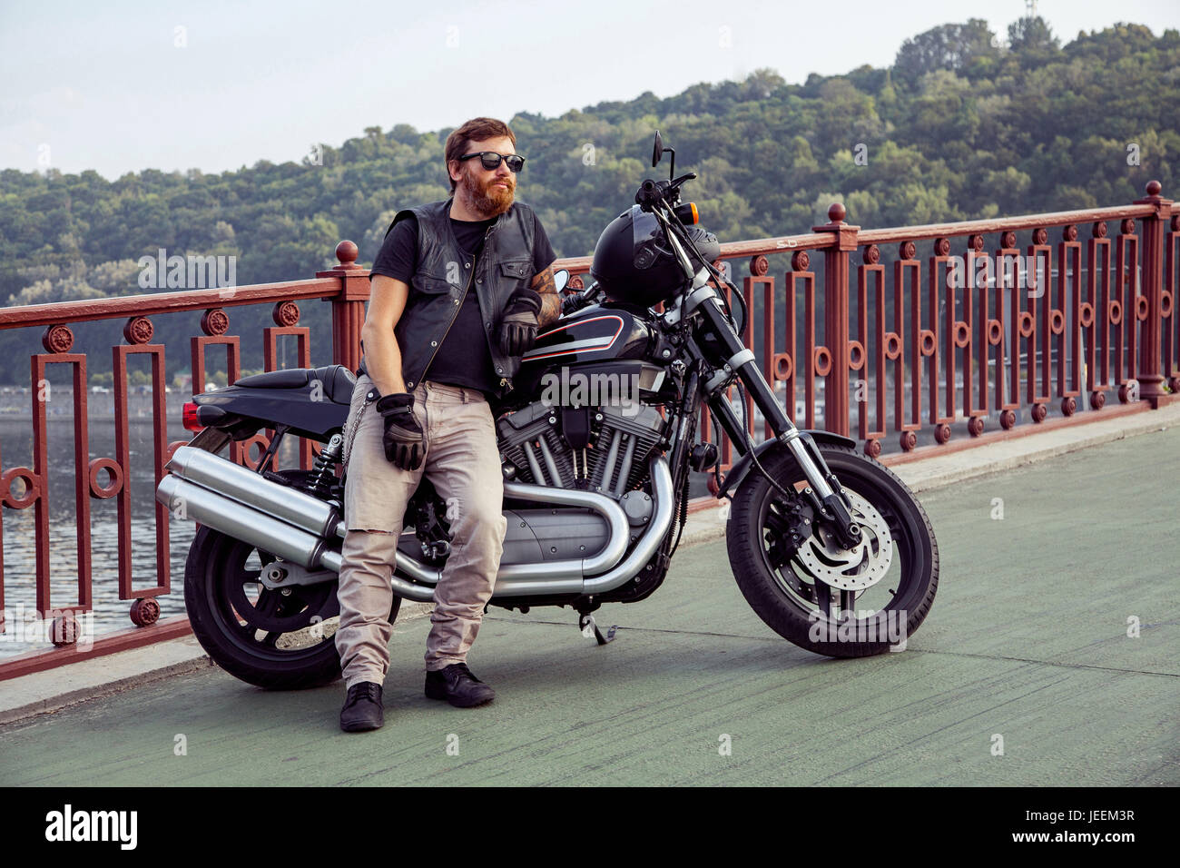 Bearded redhead biker with beard in leather jacket near bike. Stock Photo