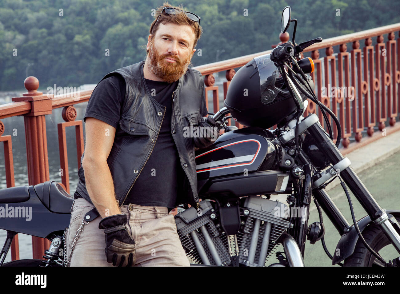 Bearded redhead biker with beard in leather jacket near bike. Stock Photo