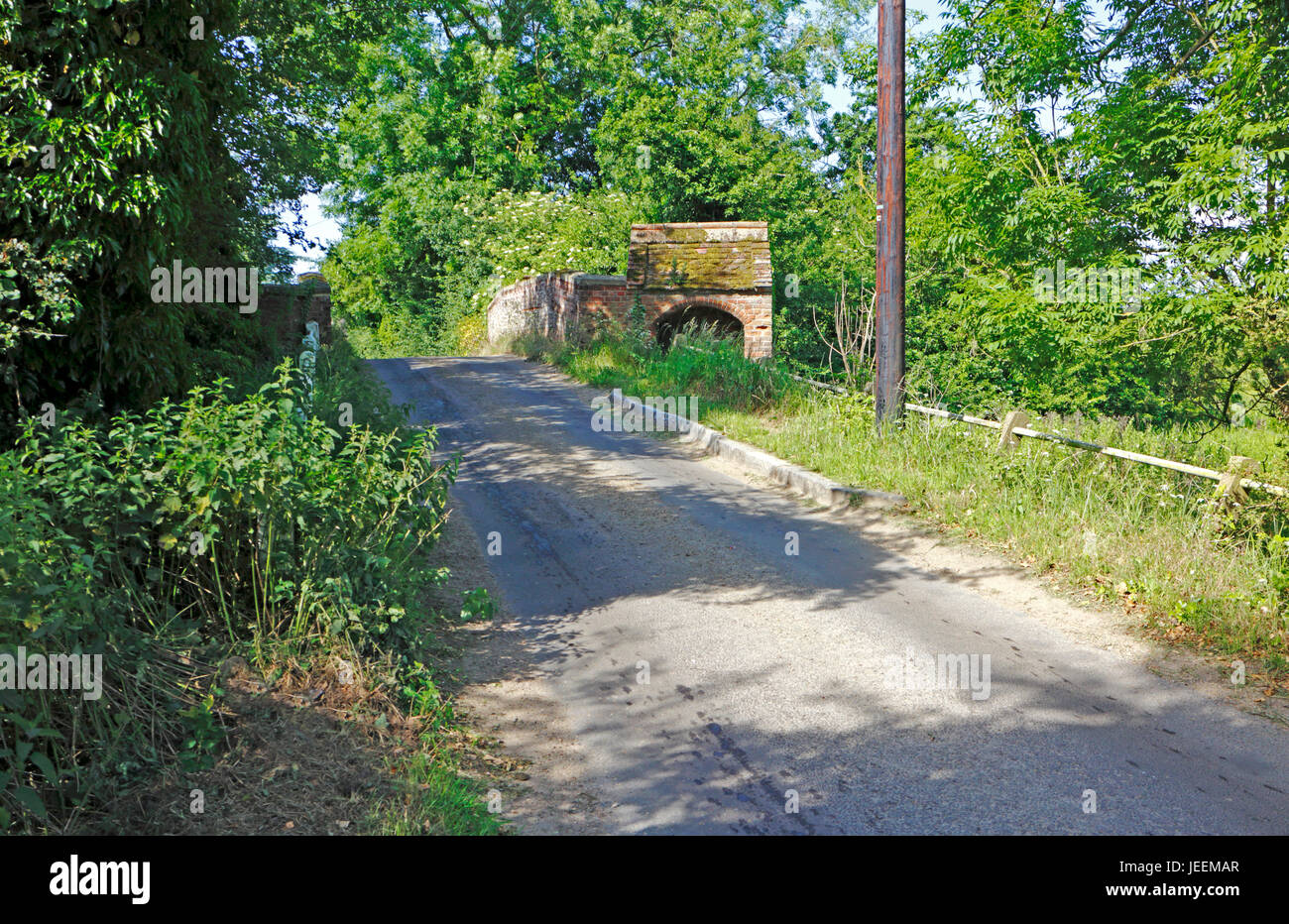 A view of a narrow country road passing over the Grade Two listed Mayton Bridge at Little Hautbois, Norfolk, England, United Kingdom. Stock Photo