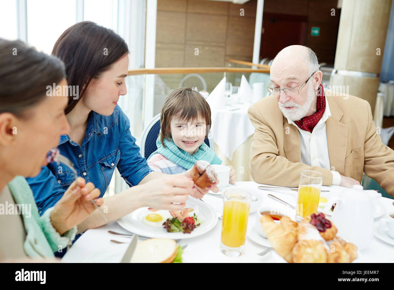 Happy family sitting by table and having breakfast Stock Photo - Alamy