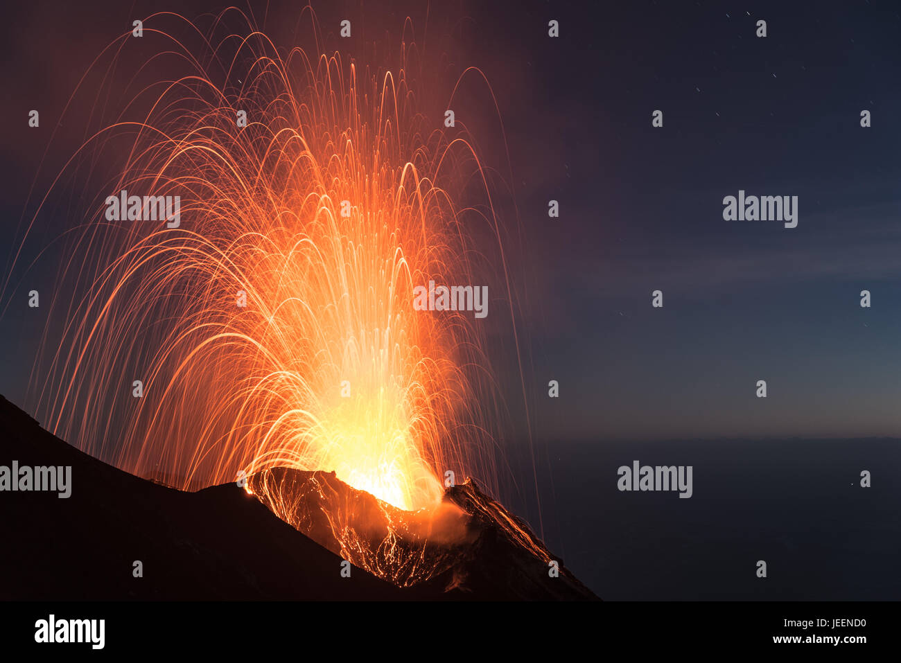 Strong strombolian volcanic eruption from Stromboli volcano (Eolian Islands, Lipari, Italy) at night, craters illuminated by moonlight, June 2017 Stock Photo
