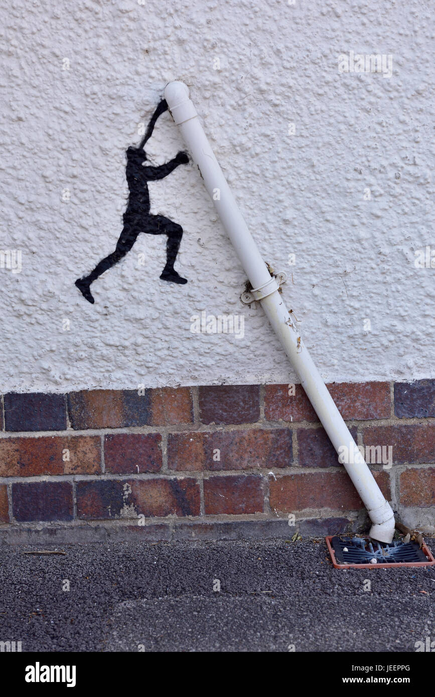 A bit of whimsy, silhouette painting on wall of person supporting an angled drain pipe Stock Photo