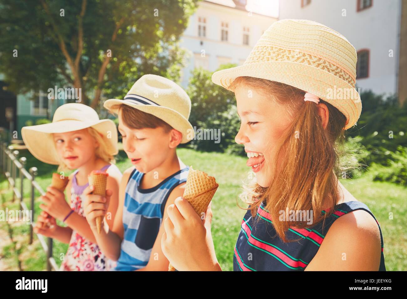 Summer day in the city. Cute siblings with hats eating big ice cream in the park. Stock Photo
