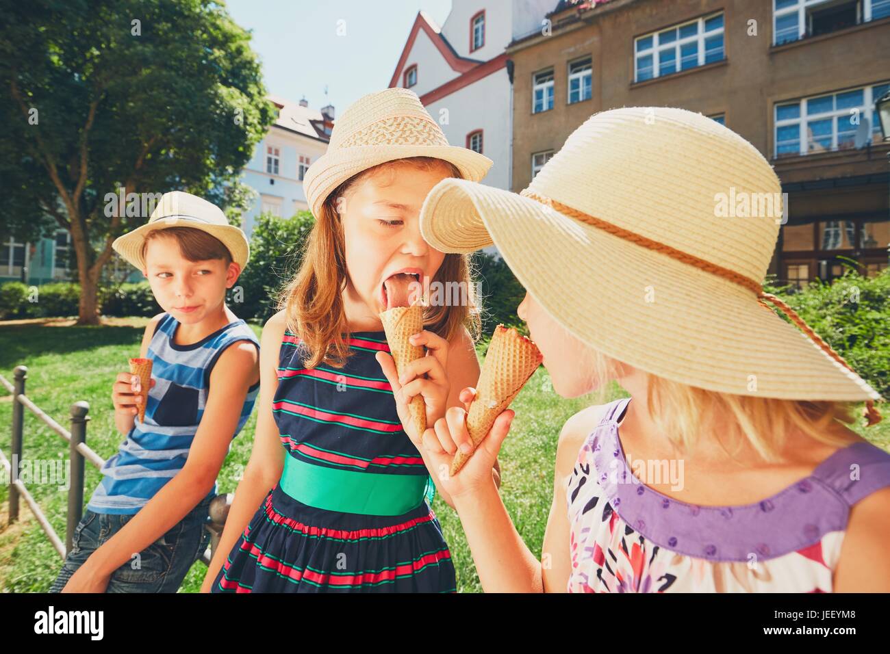 Summer day in the city. Cute siblings with hats eating big ice cream in the park. Stock Photo