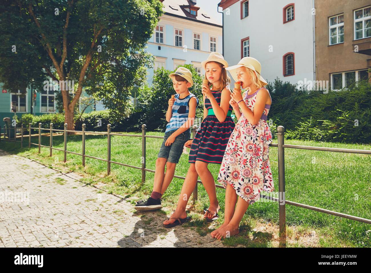 Summer day in the city. Cute siblings with hats eating big ice cream in the park. Stock Photo