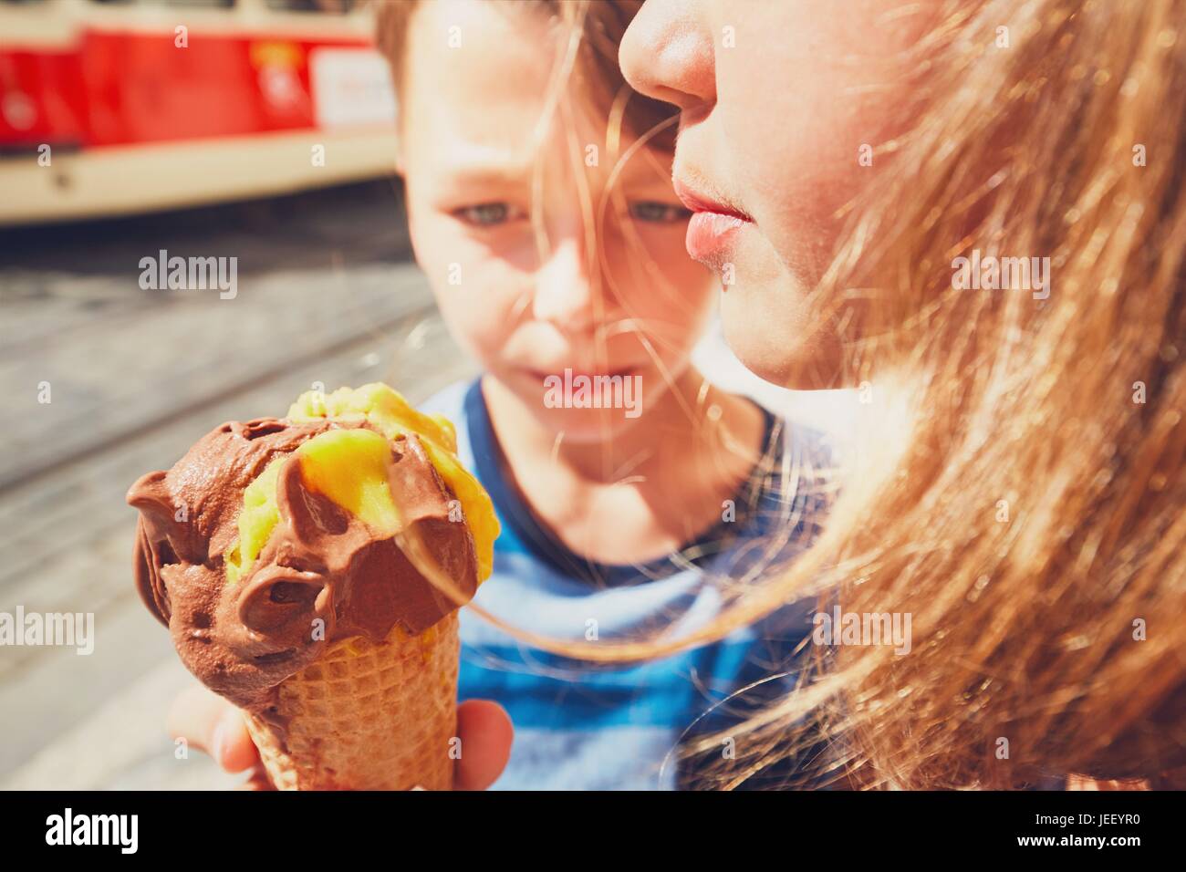 Summer day in the city. Cute siblings with hats eating big ice cream. Selective focus on the mouth. Stock Photo