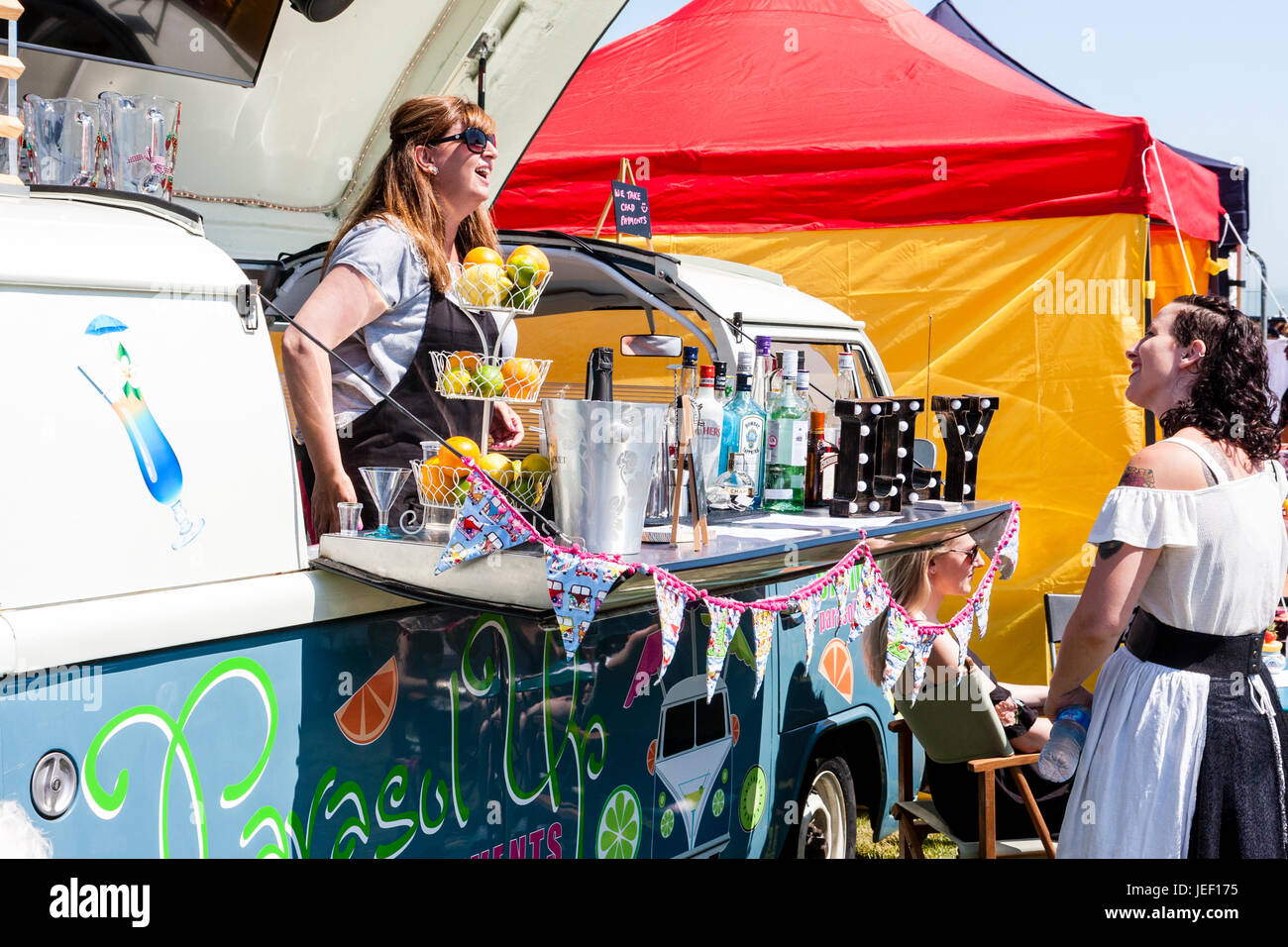 VW camper van turned into a mobile bar. Roof hinged up with woman