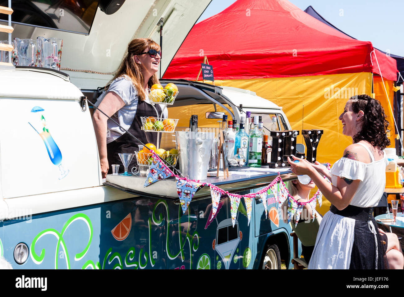 VW camper van turned into a mobile bar. Roof hinged up with woman