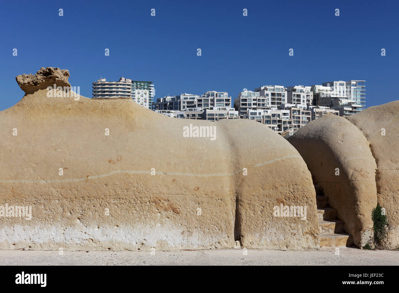 Ocher colored limestone sand formation at St. Elmo Bay from Valletta, view of residential blocks on the Tigné spit of land Stock Photo