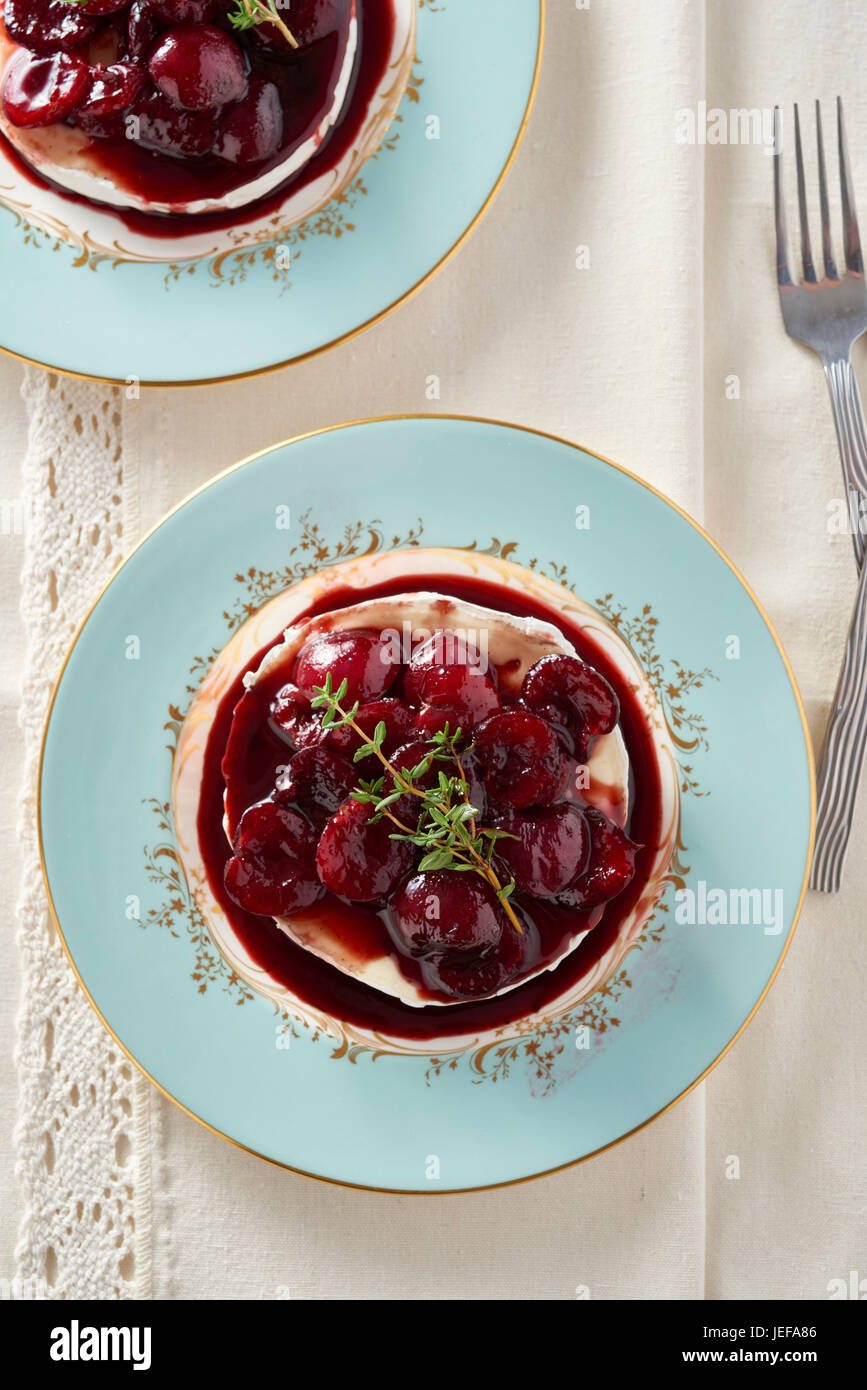 Brie cheese with warm cherry compote served on a blue plate Stock Photo