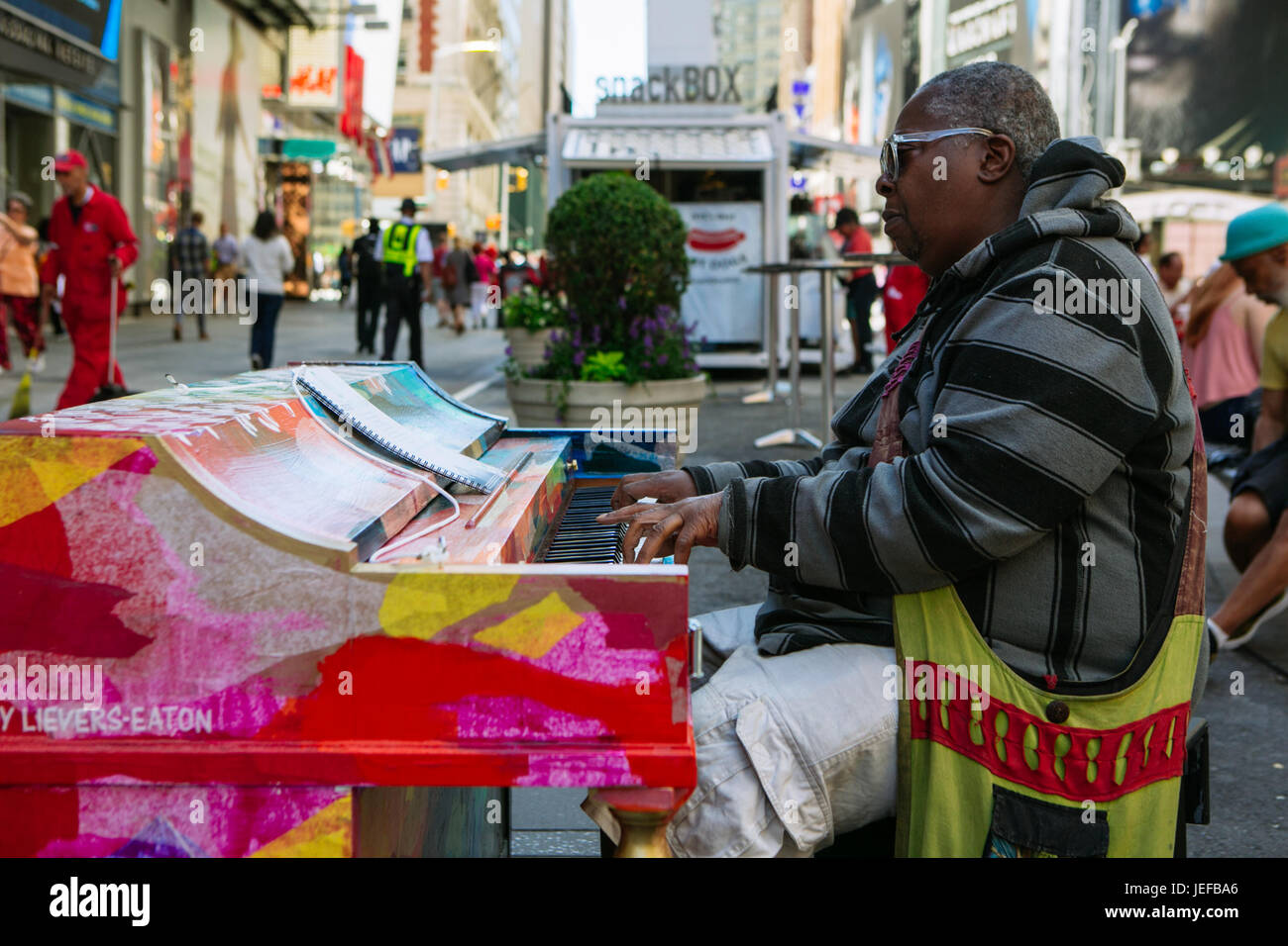 Afroamerican old man playing a colorful public piano in the street near Times Square, Manhattan, NYC, USA Stock Photo