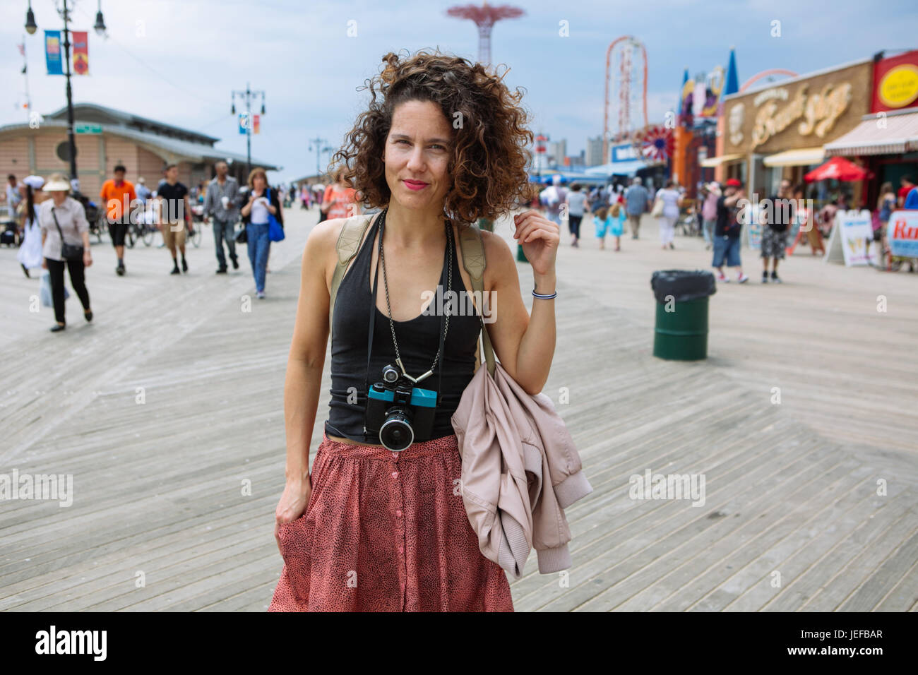 Cool beautiful woman with a Diana Lomography camera holding her neck in Coney Island boardwalk during summer weekend, Brooklyn, USA Stock Photo