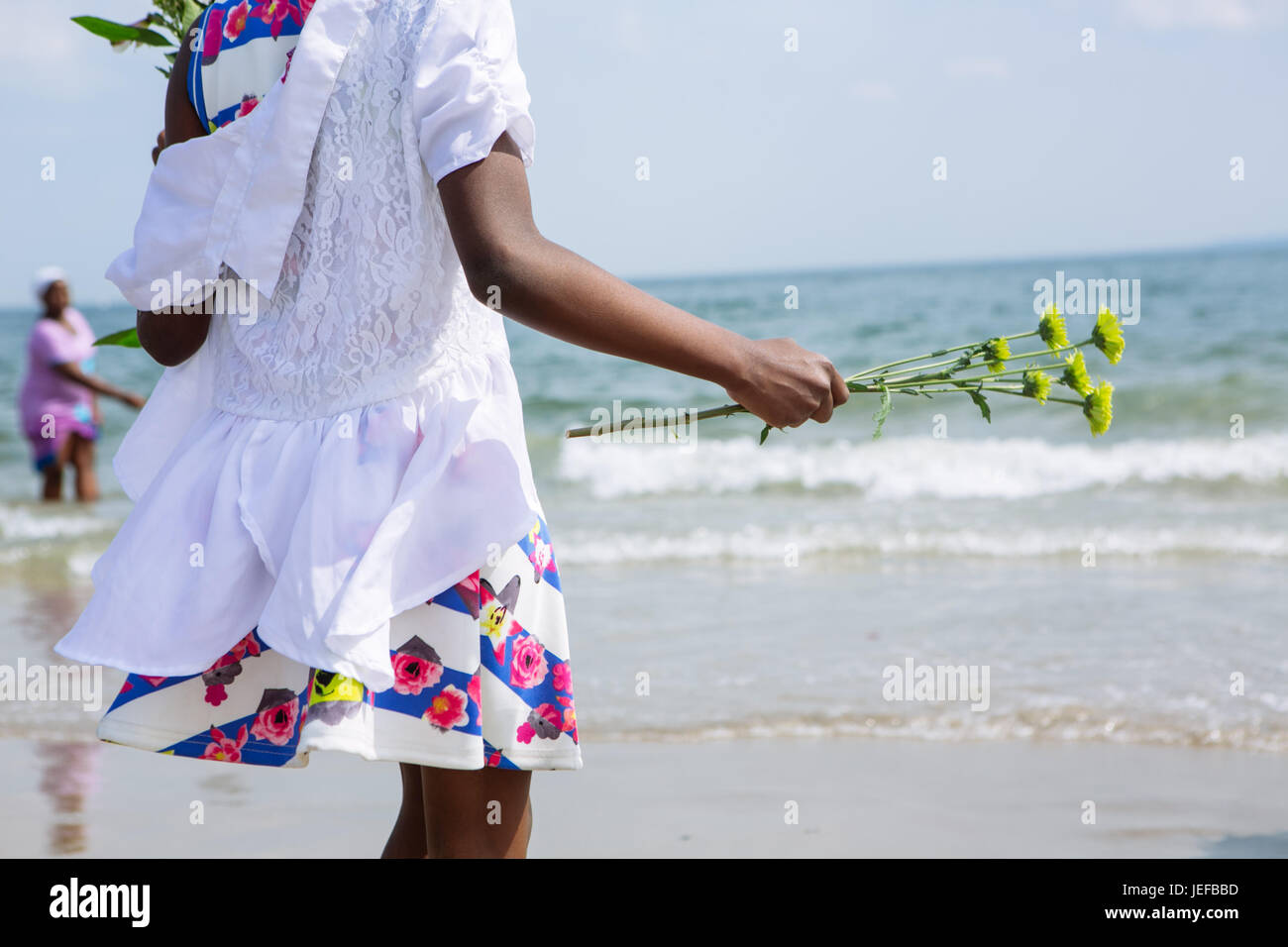 Young black girl about to throw flowers to the Ocean in Coney Island