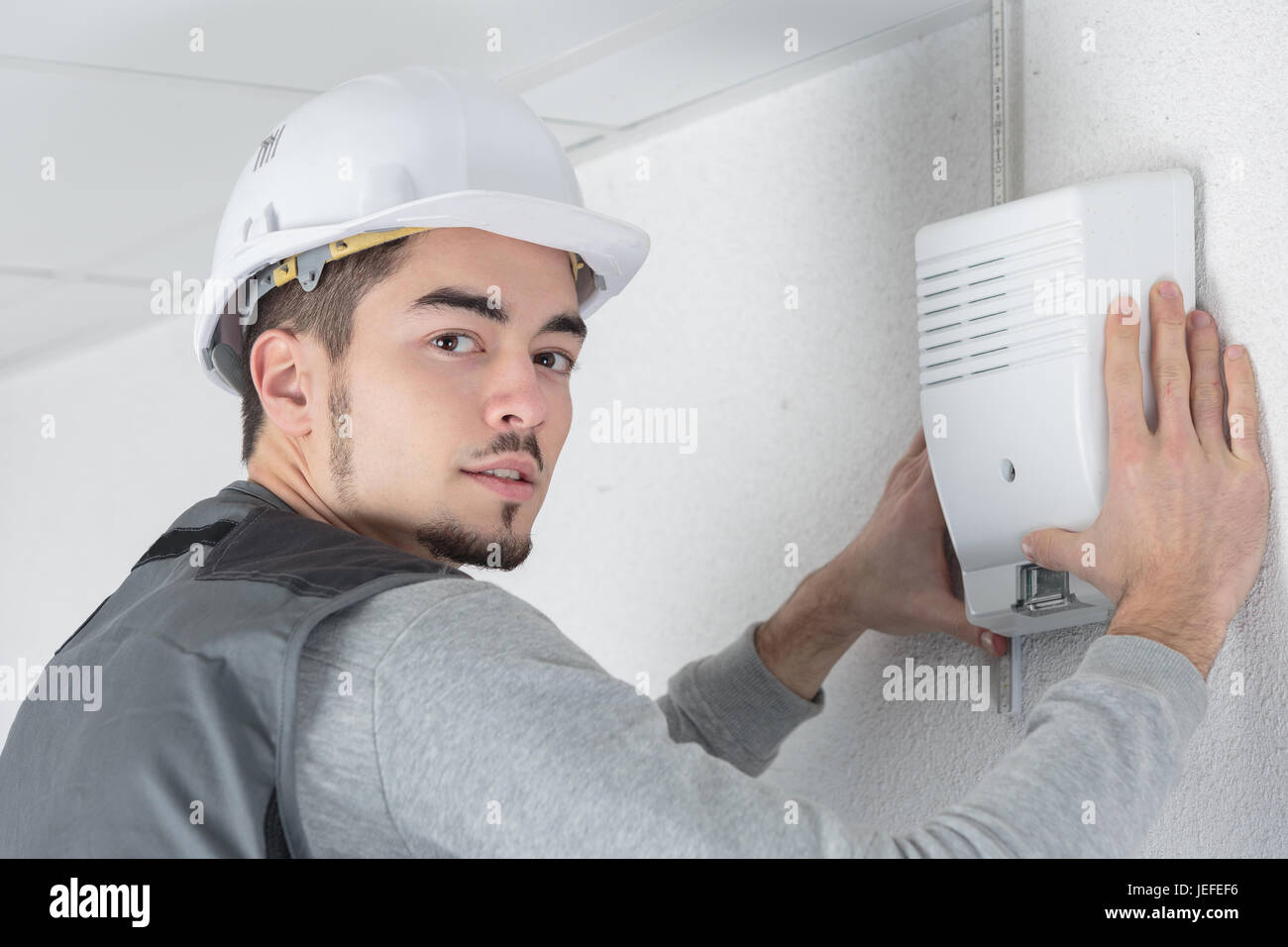 electrician fitting a thermostat system Stock Photo Alamy