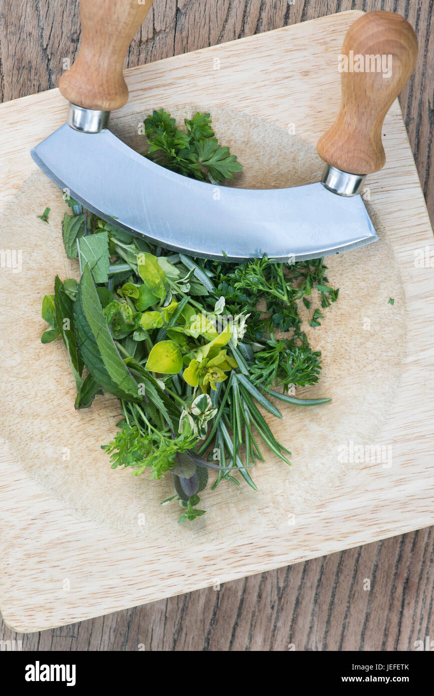 Freshly chopped green coriander on a light wood chopping board with a  mezzaluna herb chopper Stock Photo - Alamy