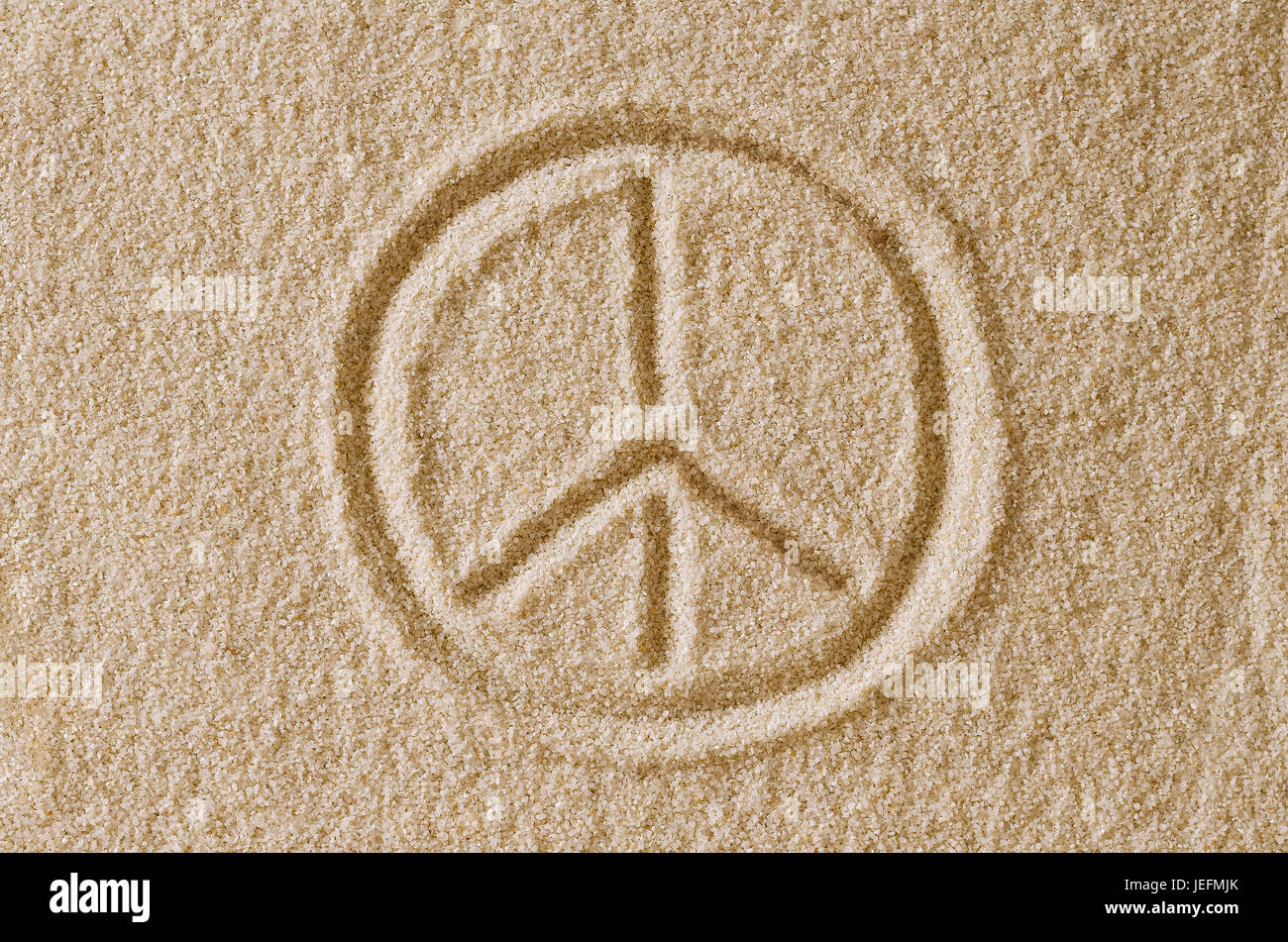 Peace Sign drawn in sand. Imprint and shape of the Pace Symbol in ocher grains of sand. Also a symbol for antiwar, love and counterculture. Stock Photo