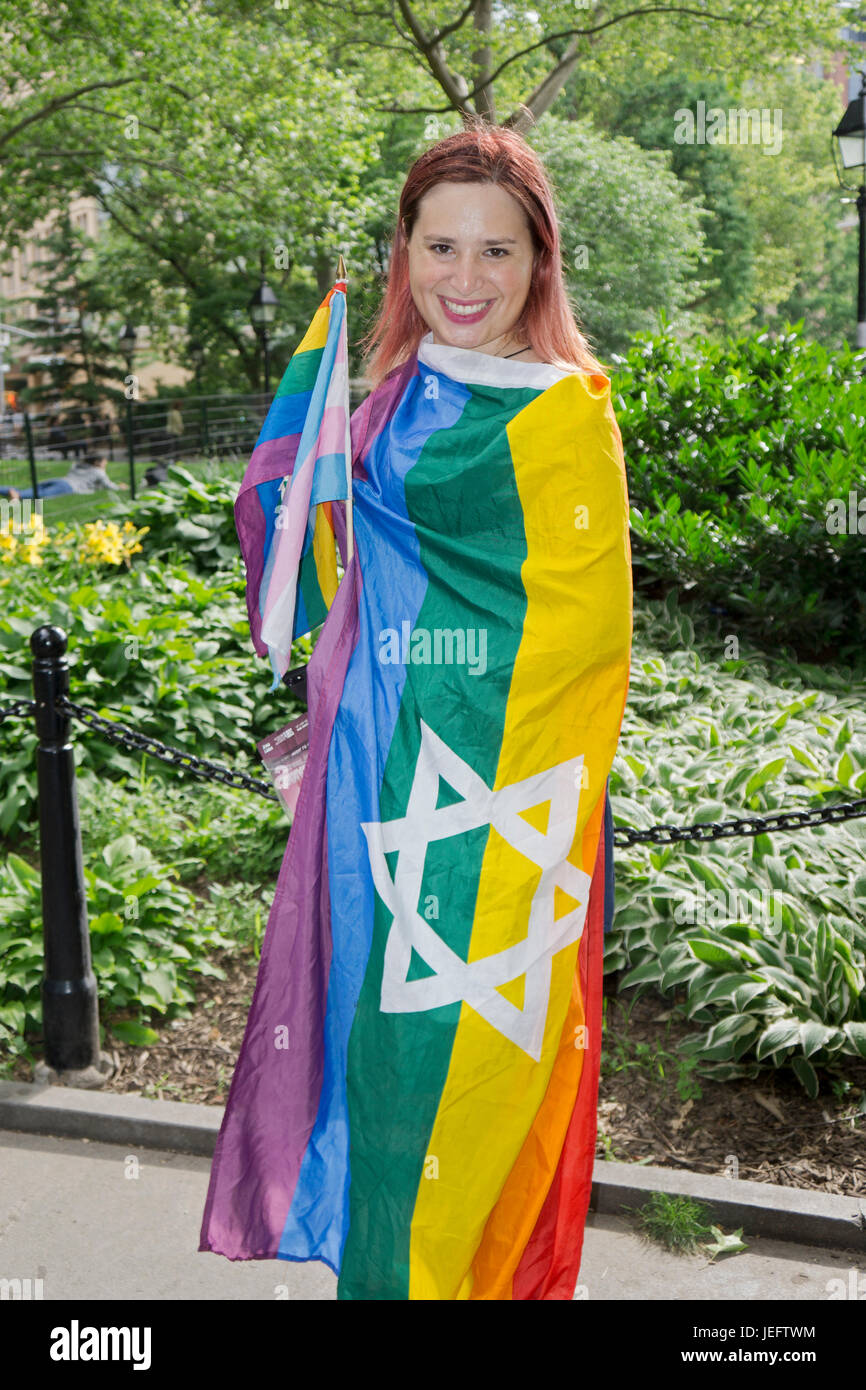A Jewish transr woman wrapped in an LGBT flag with a Star if David at a transgender rally in Washington Square Park in New York City. Stock Photo