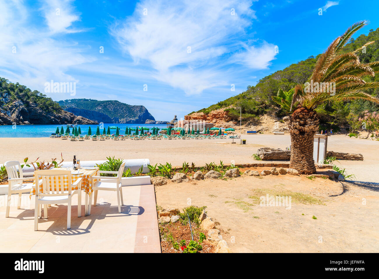 Restaurant table on sunny terrace on Cala Benirras beach, Ibiza island, Spain Stock Photo