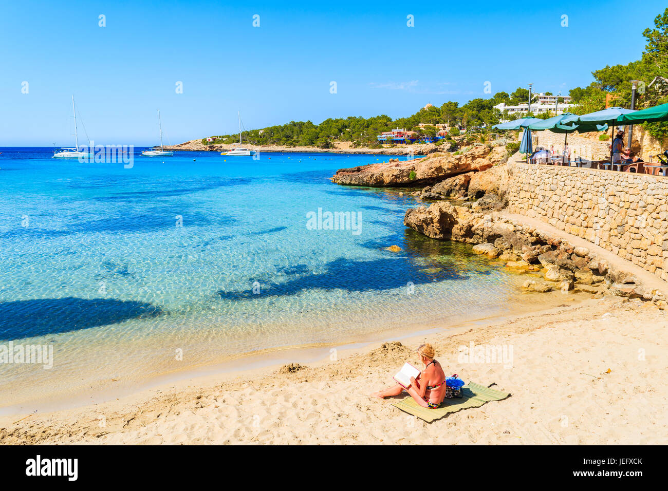 CALA PORTINATX, ISLAND MAY 22, 2017 woman sitting on beach and