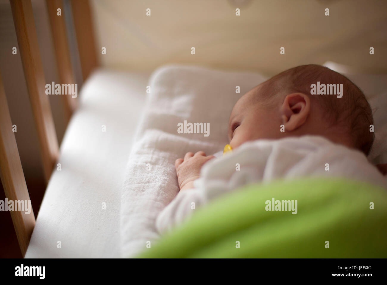 Newborn baby in crib with nipple in mouth Stock Photo