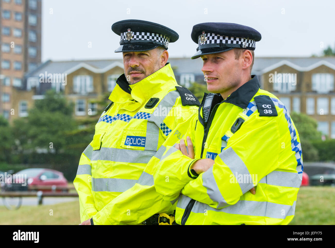 Pair of male police officers keeping watch at an outdoor event in the rain. UK Sussex Police officers. Stock Photo