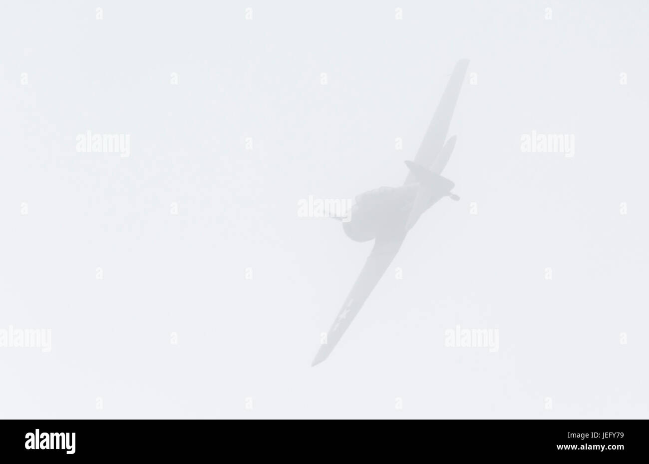 Military propeller aircraft flying an air display in fog. Flying in mist. Foggy conditions. Misty conditions. Stock Photo