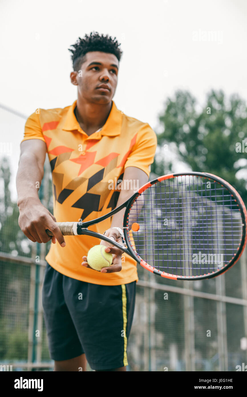 Low angle view of determined young black man playing tennis Stock Photo