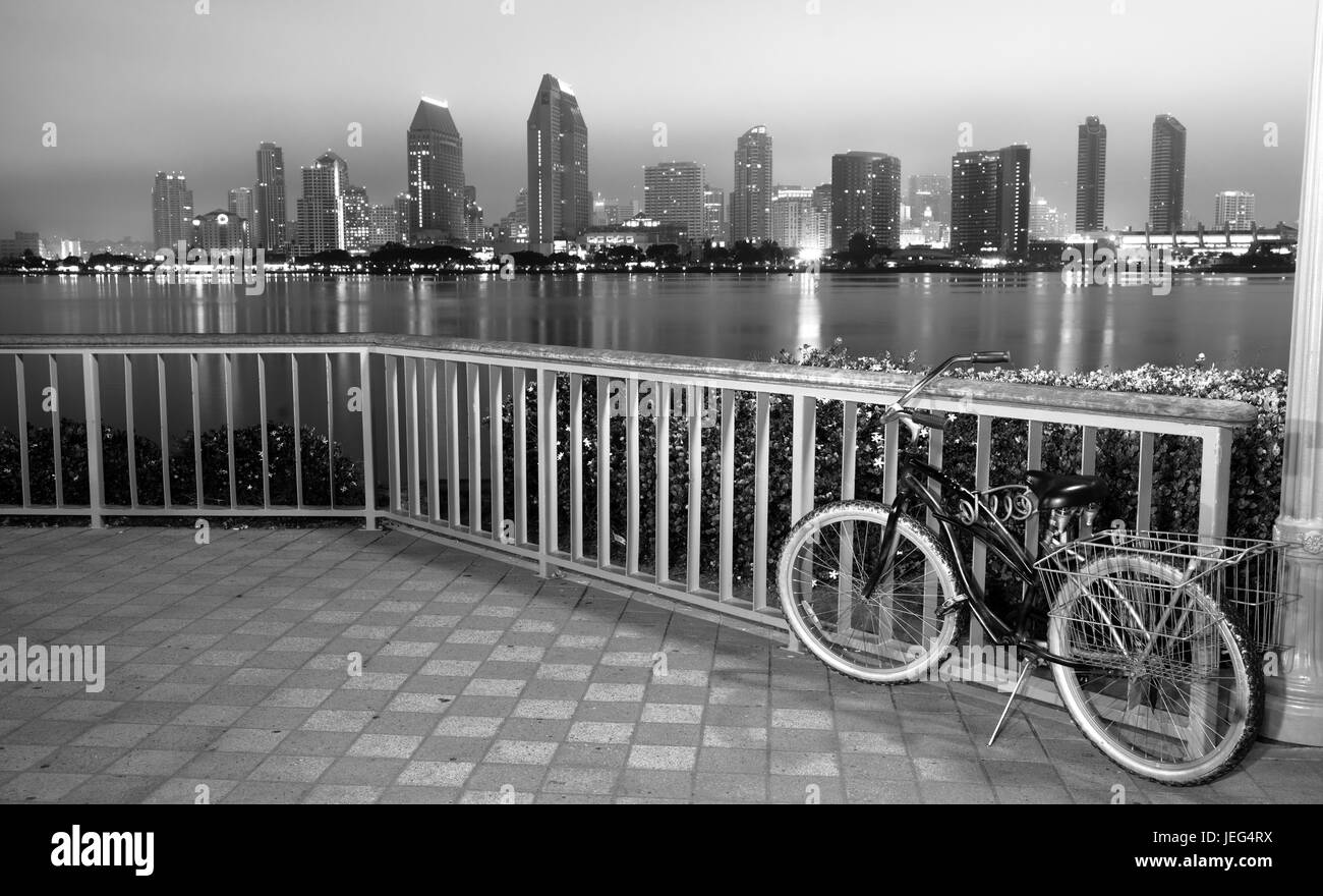 A bike is locked to the fence in Coronado with San Diego in the background at night Stock Photo