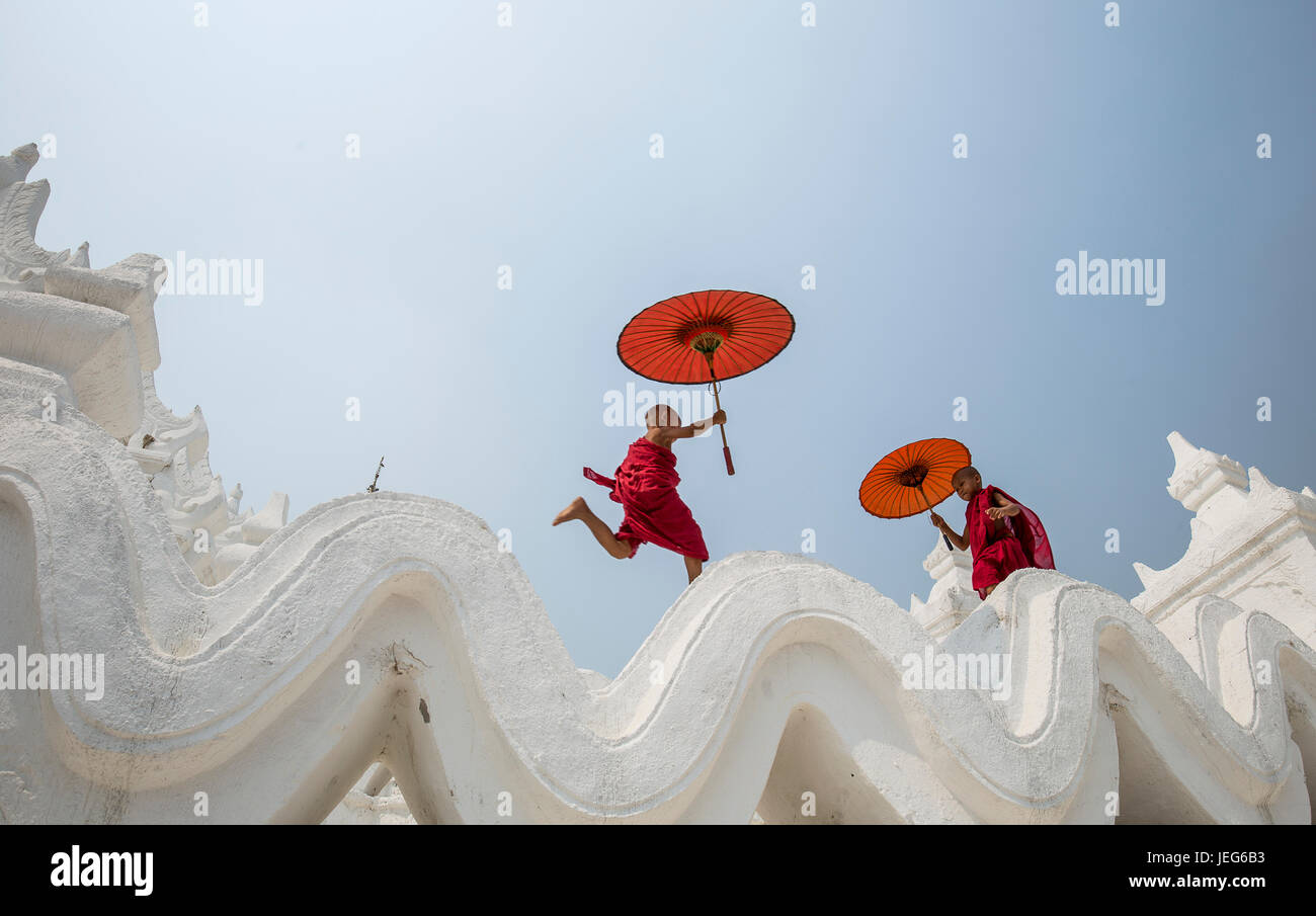 Monks with umbrella in Hsinbyume Pagoda Temple in Mandalay Myanmar Mingon Sagaing region White temple pagoda Myanmar Stock Photo