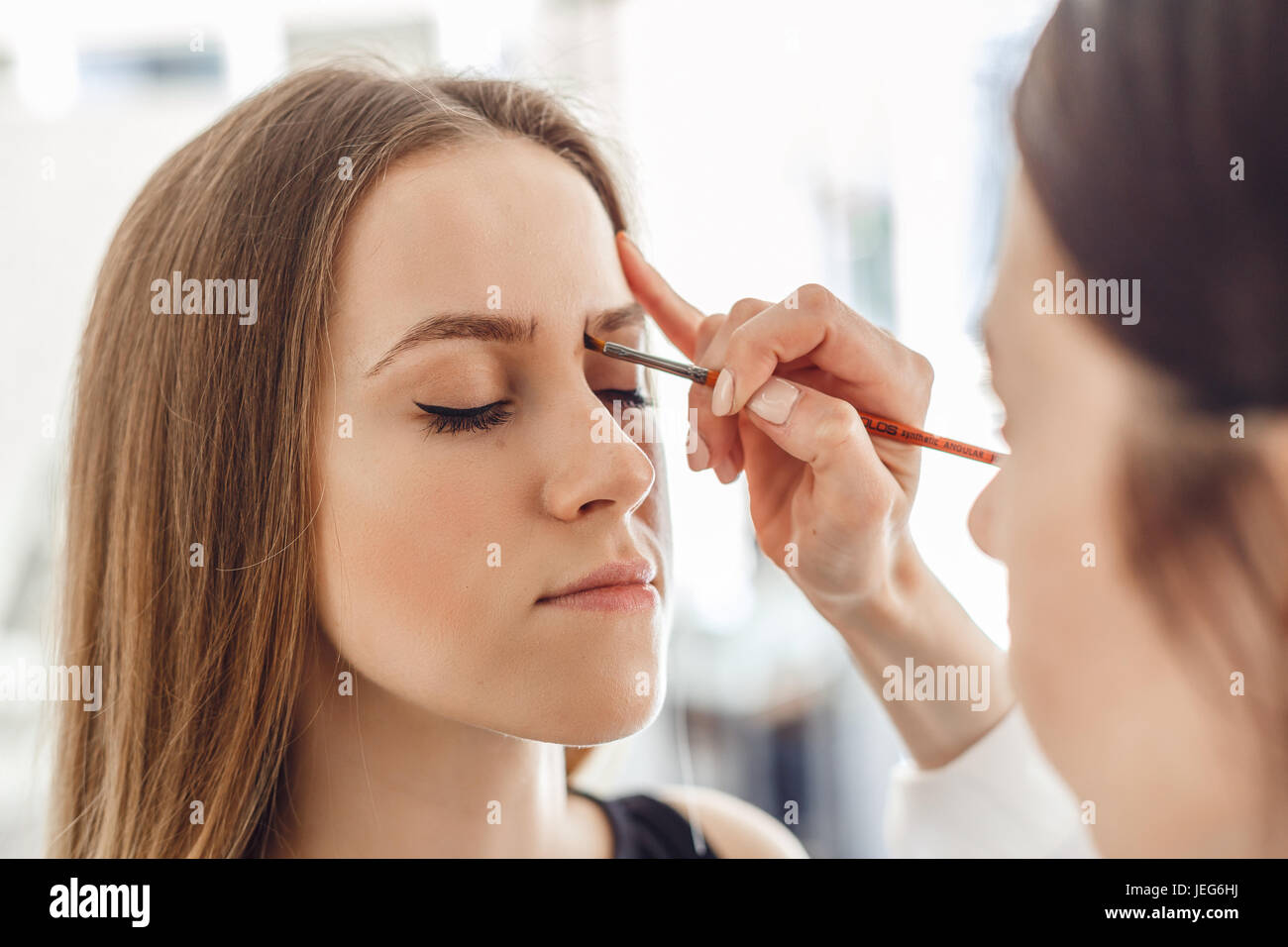 Beautiful woman drawing a shape of eyebrows using brush pencil Stock Photo