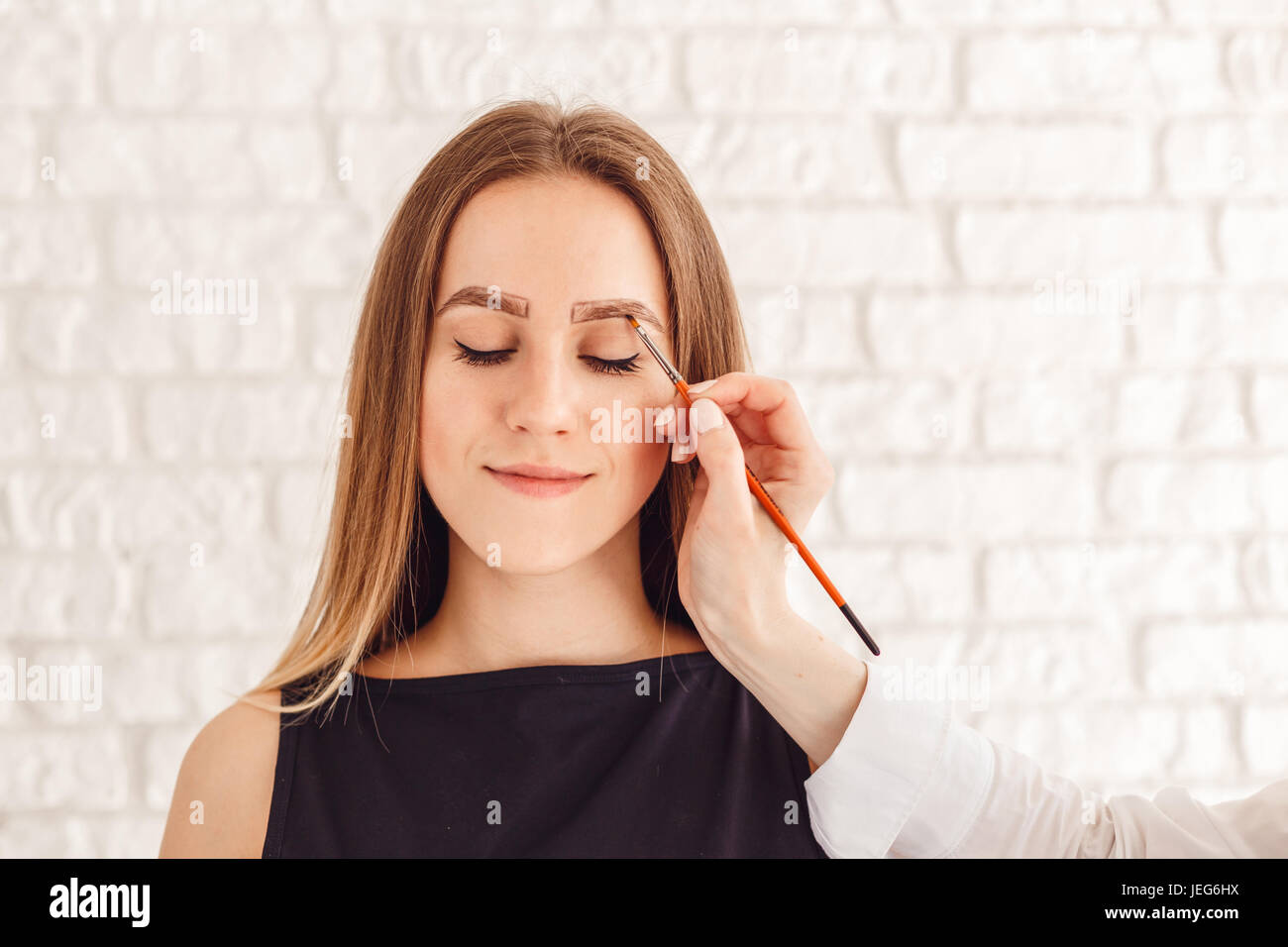 Eyebrow correction procedure for the smiling model with long eyelashes Stock Photo