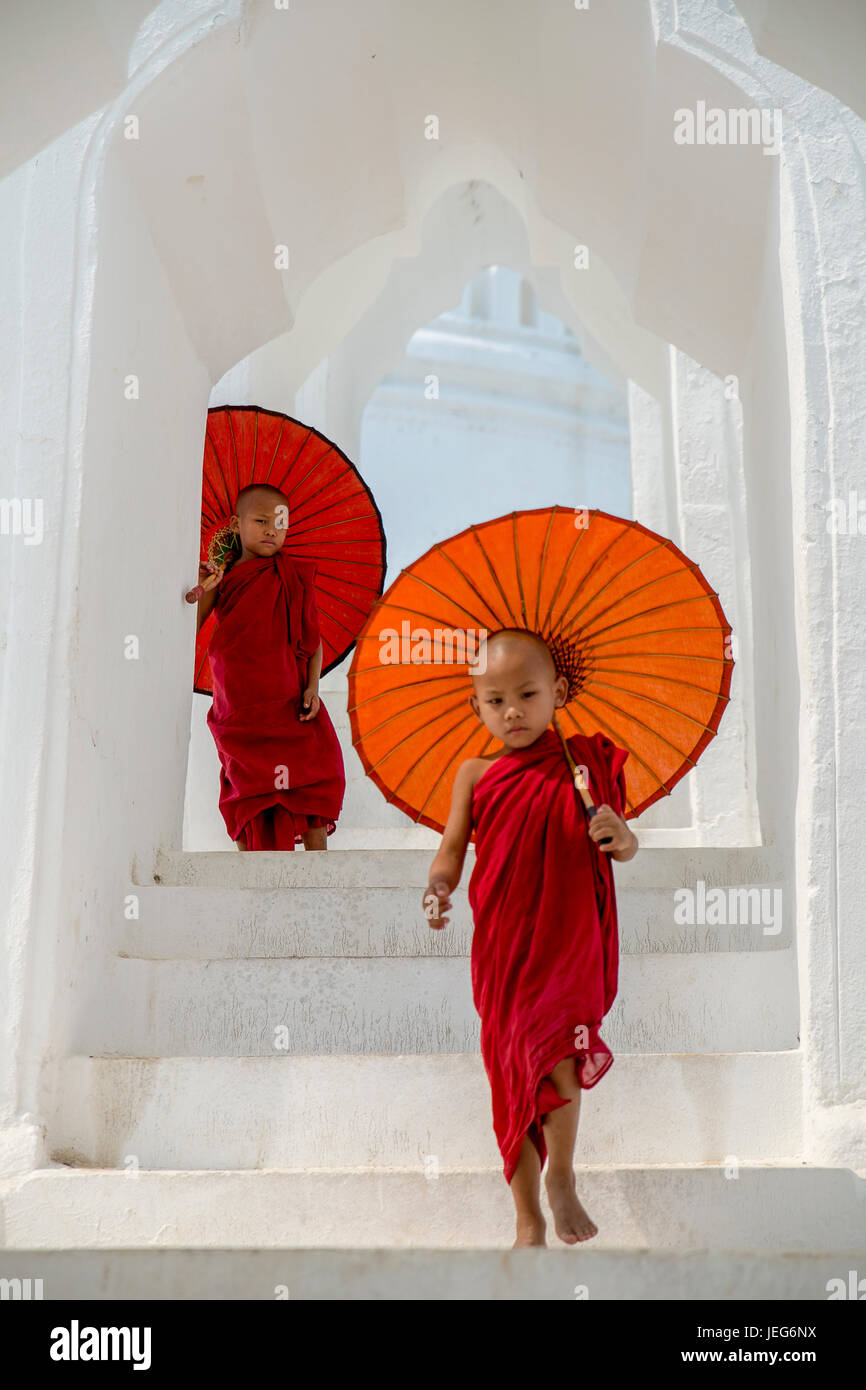 Monks with umbrella in Hsinbyume Pagoda Temple in Mandalay Myanmar Mingon Sagaing region White temple pagoda Myanmar Stock Photo