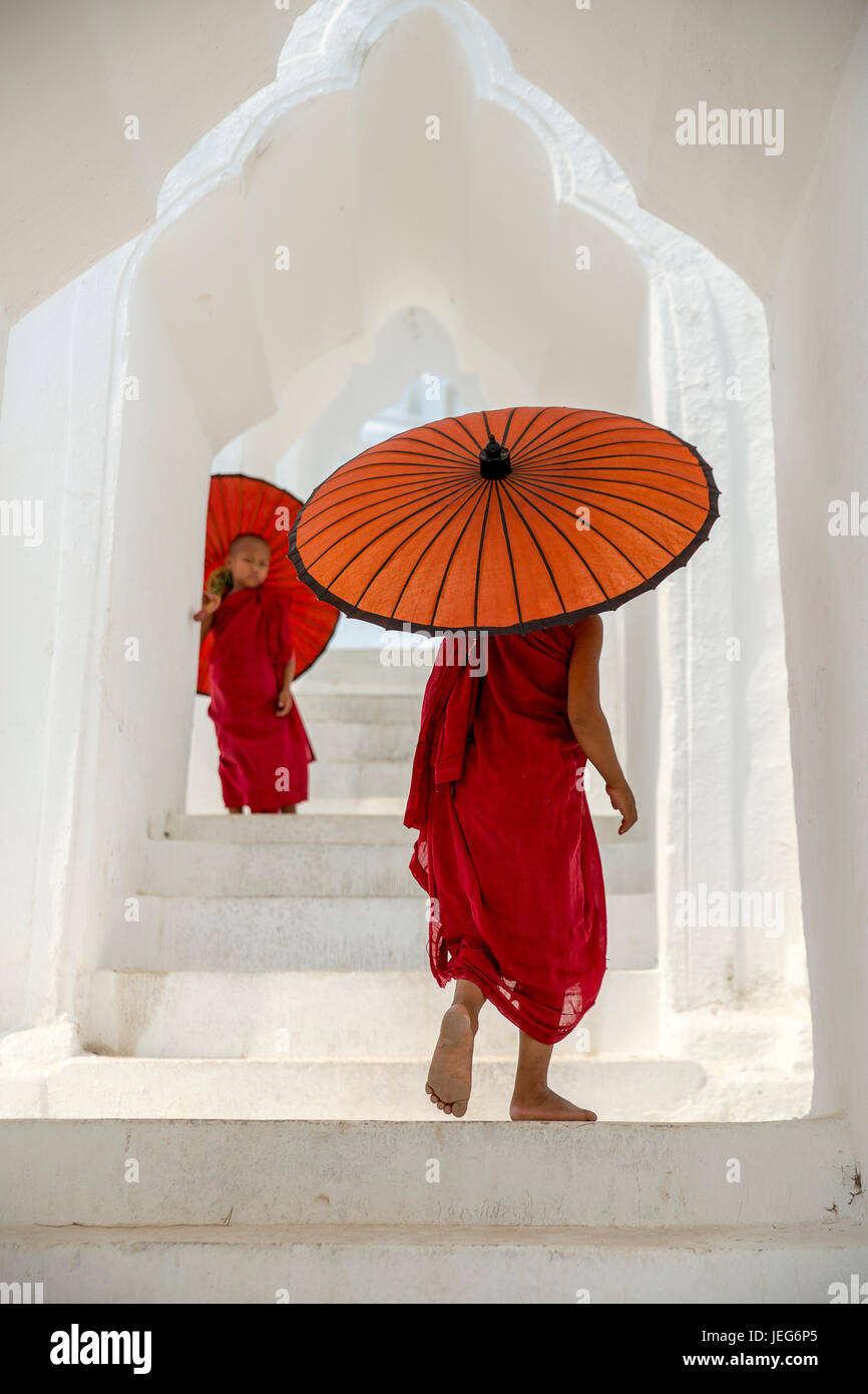 Monks with umbrella in Hsinbyume Pagoda Temple in Mandalay Myanmar Mingon Sagaing region White temple pagoda Myanmar Stock Photo