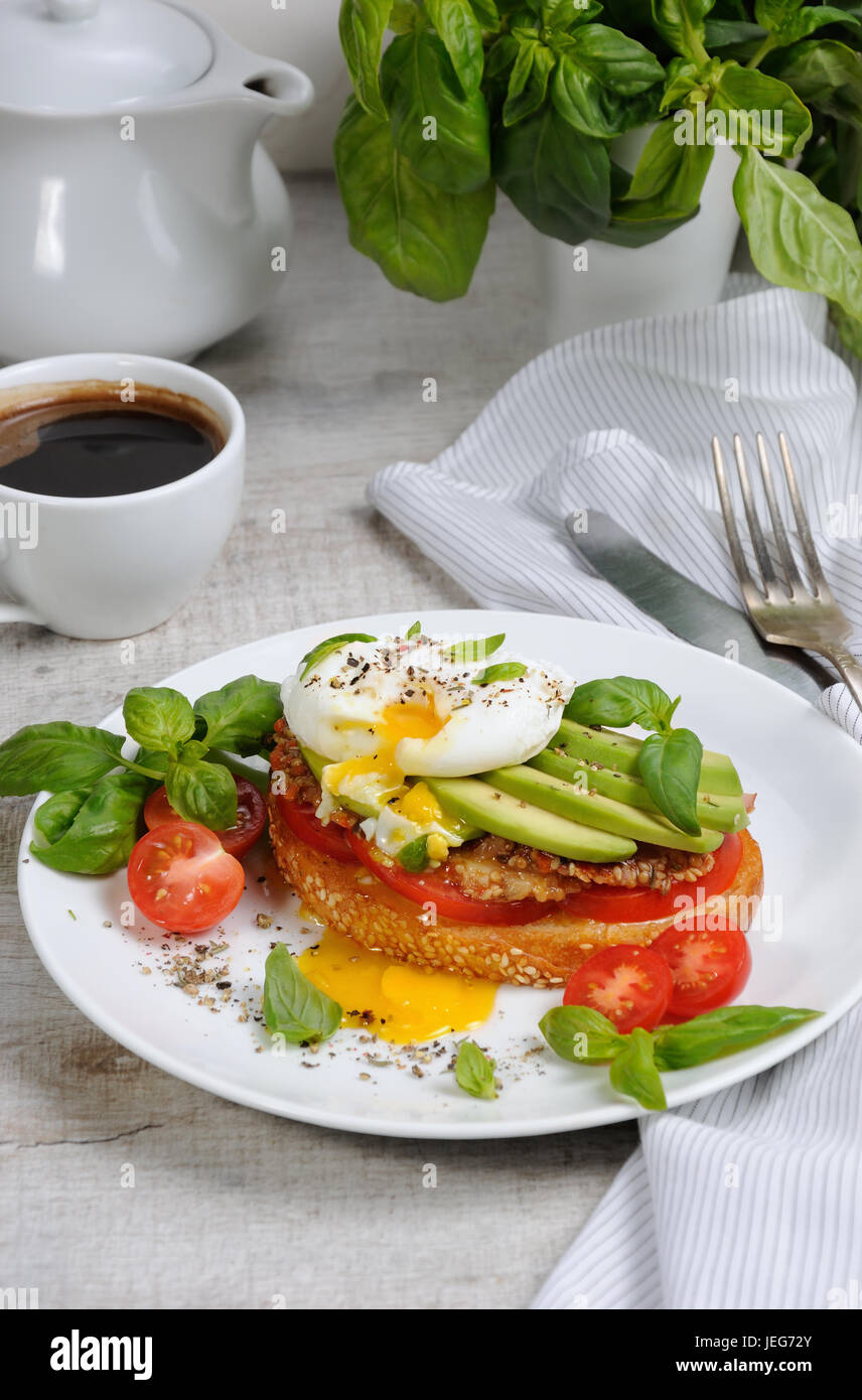 Egg poached on a toasted slice of baguette with tomato, spicy ham and avocado, sprinkled spices