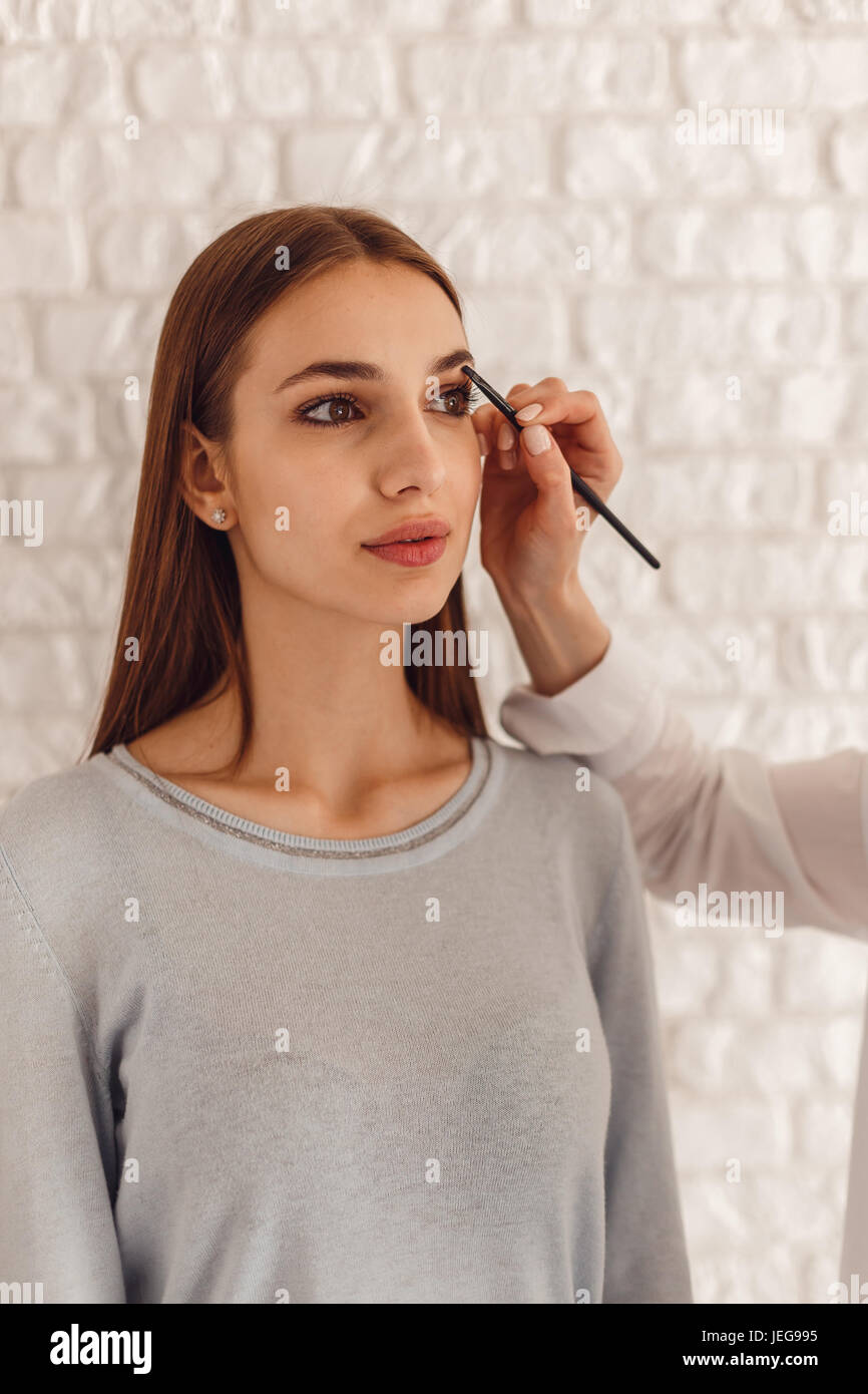 Beautiful woman and cosmetologist drawing a shape of eyebrows using cosmetic brush Stock Photo