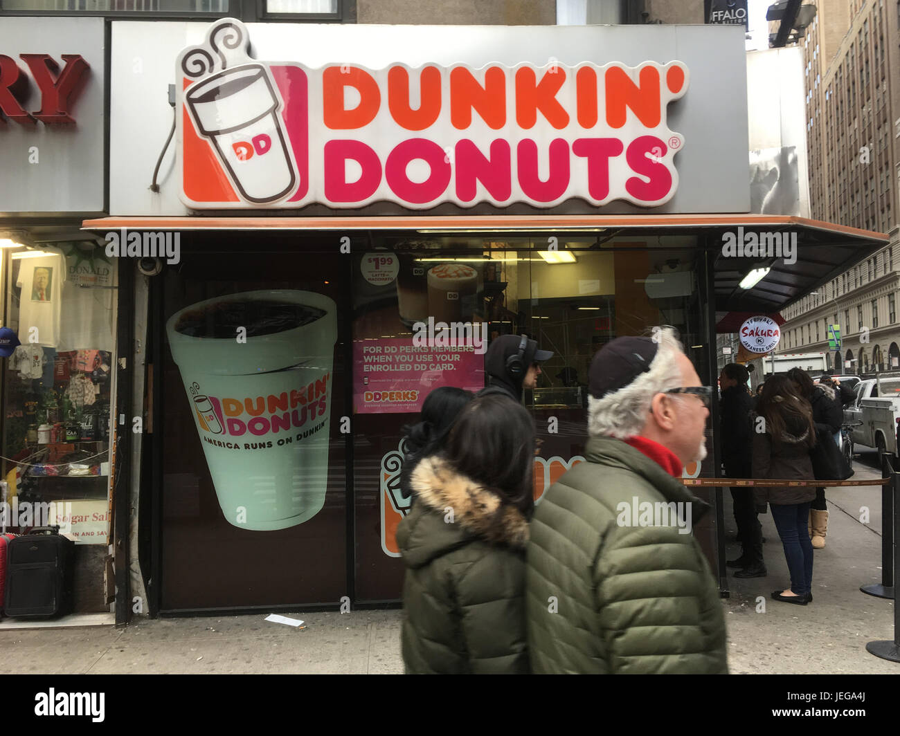 1 February 2017 - New York City: Jewish man with grey hair wearing a kippah  and wife walk passed Dunkin Donuts Coffee shop in Midtown Manhattan, NYC. Stock Photo