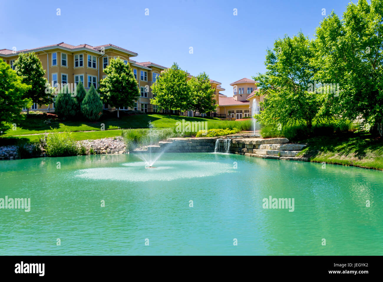 Beautiful waterfall fountain in front of Italian style building near park Stock Photo