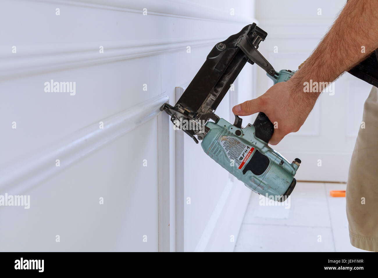 Carpenter using a brad nail gun to complete framing trim Stock Photo