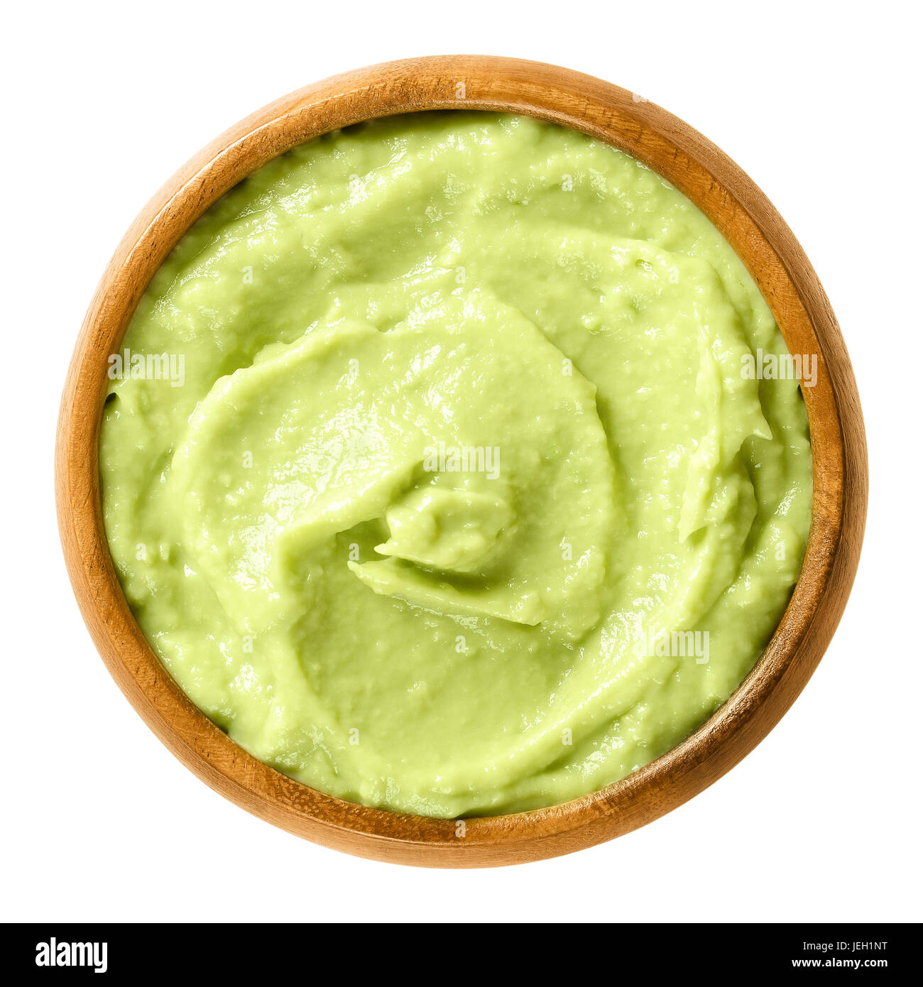 Avocado cream in wooden bowl. Alligator pear, the fruit of the Persea americana tree. Light green paste of mashed avocados and lemon juice. Photo. Stock Photo