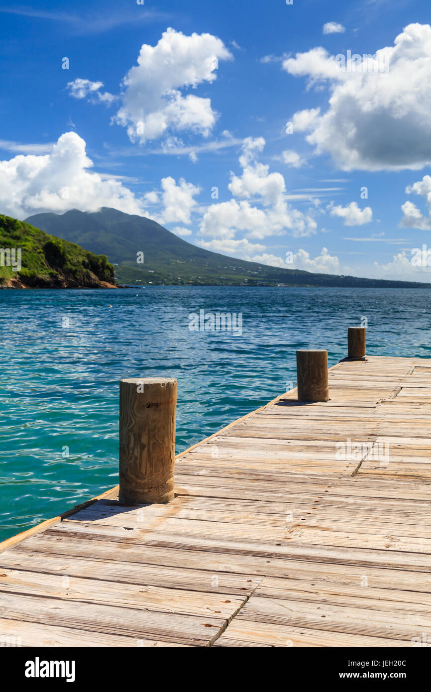 Cockleshell Bay Pier.  The pier is located on Cockleshell Bay on the Caribbean island of St. Kitts in the West Indies.  Nevis is in the background. Stock Photo