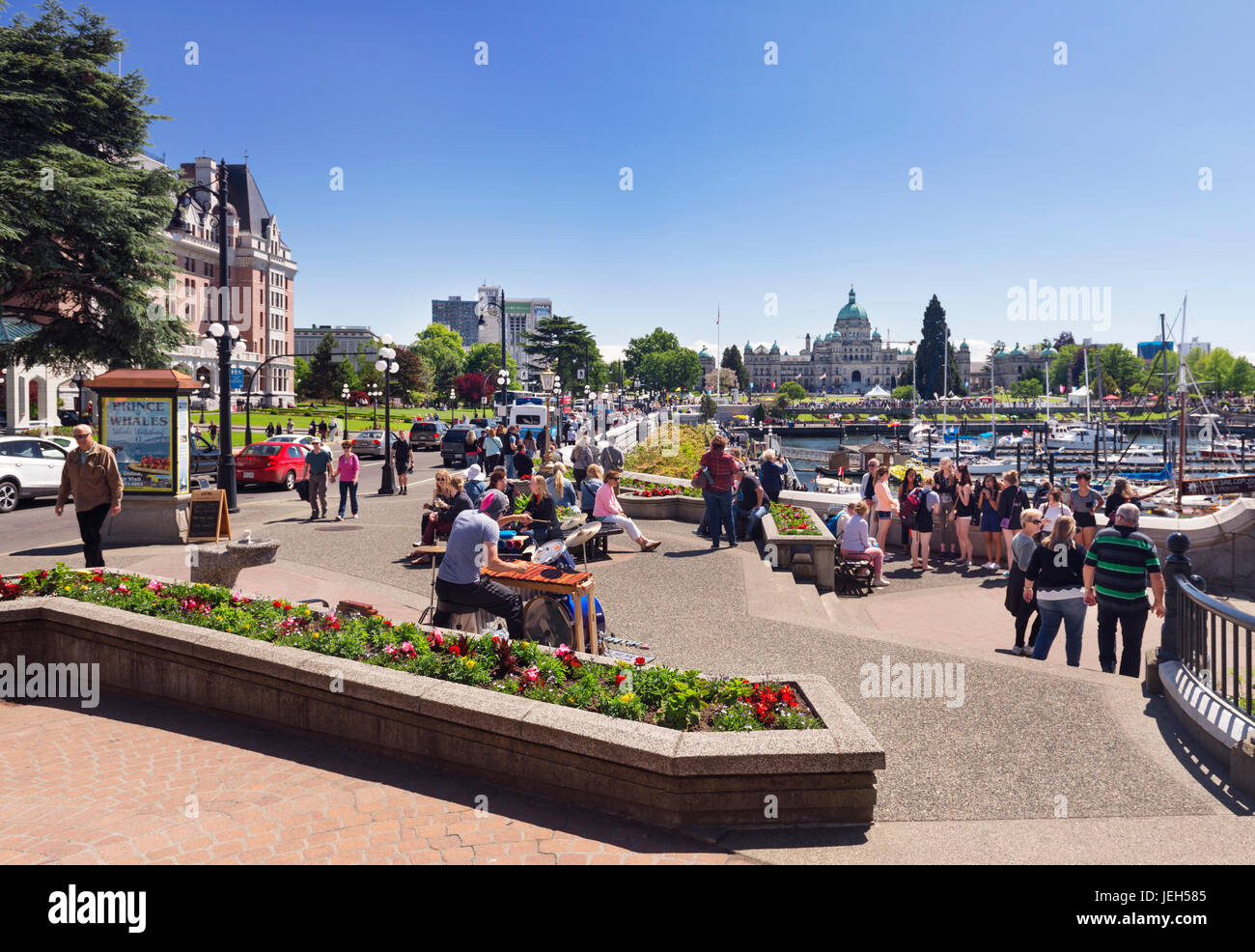 People in downtown Victoria, BC on a sunny summer day listening to a drummer, street musician. Wharf and Government Streets. Victoria, Vancouver Islan Stock Photo