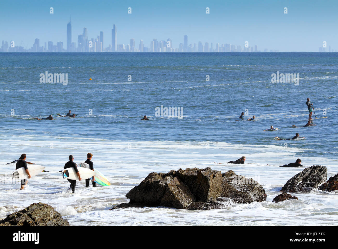 Three men and surfboards walking into the surf. Stock Photo