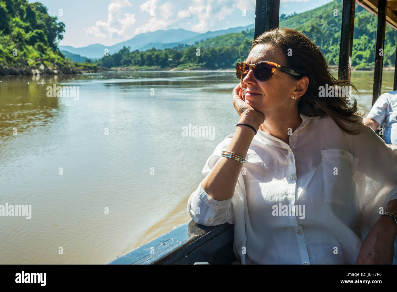 A woman in sunglasses sits in a tour boat looking out the window while