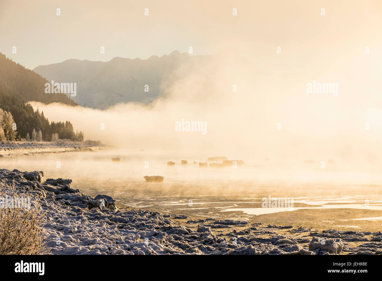 Low Altitude Fog Is Cast In Warm Sunset Light Along Turnagain Arm And The Seward Highway In Winter, Sea Ice Covering The Ocean In The Foreground, T... Stock Photo