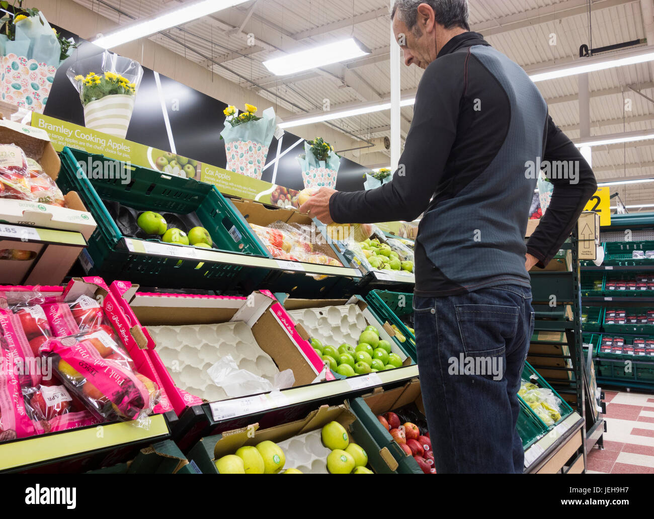 Mature male shopper checking price of fruit in Tesco supermarket. UK. Cost of living crisis, inflation, rising food prices... Stock Photo