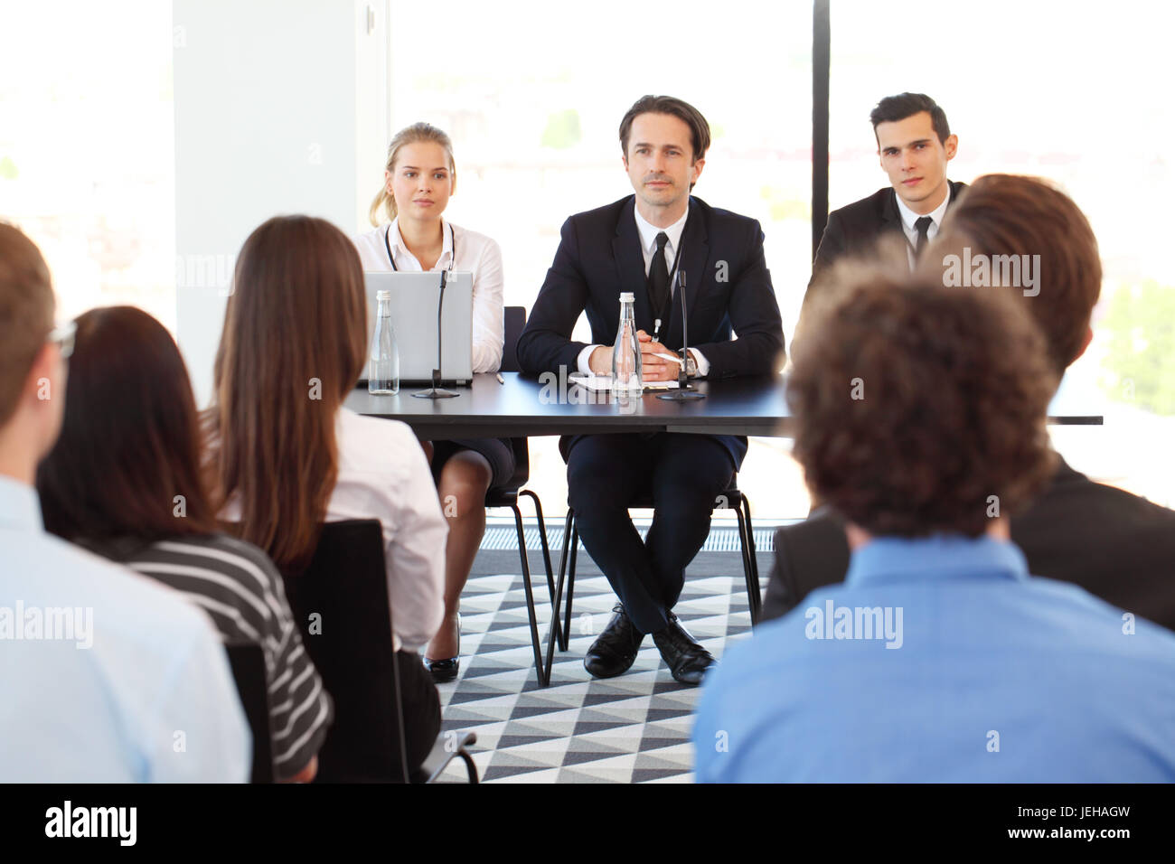 Group of speakers at business meeting at the table with microphones ...